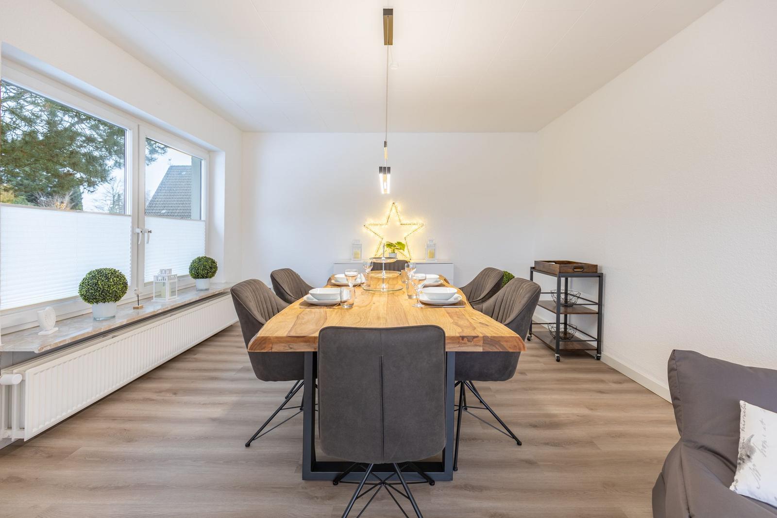 Esszimmer mit Holztisch, grauen Stühlen und Fensterblick.