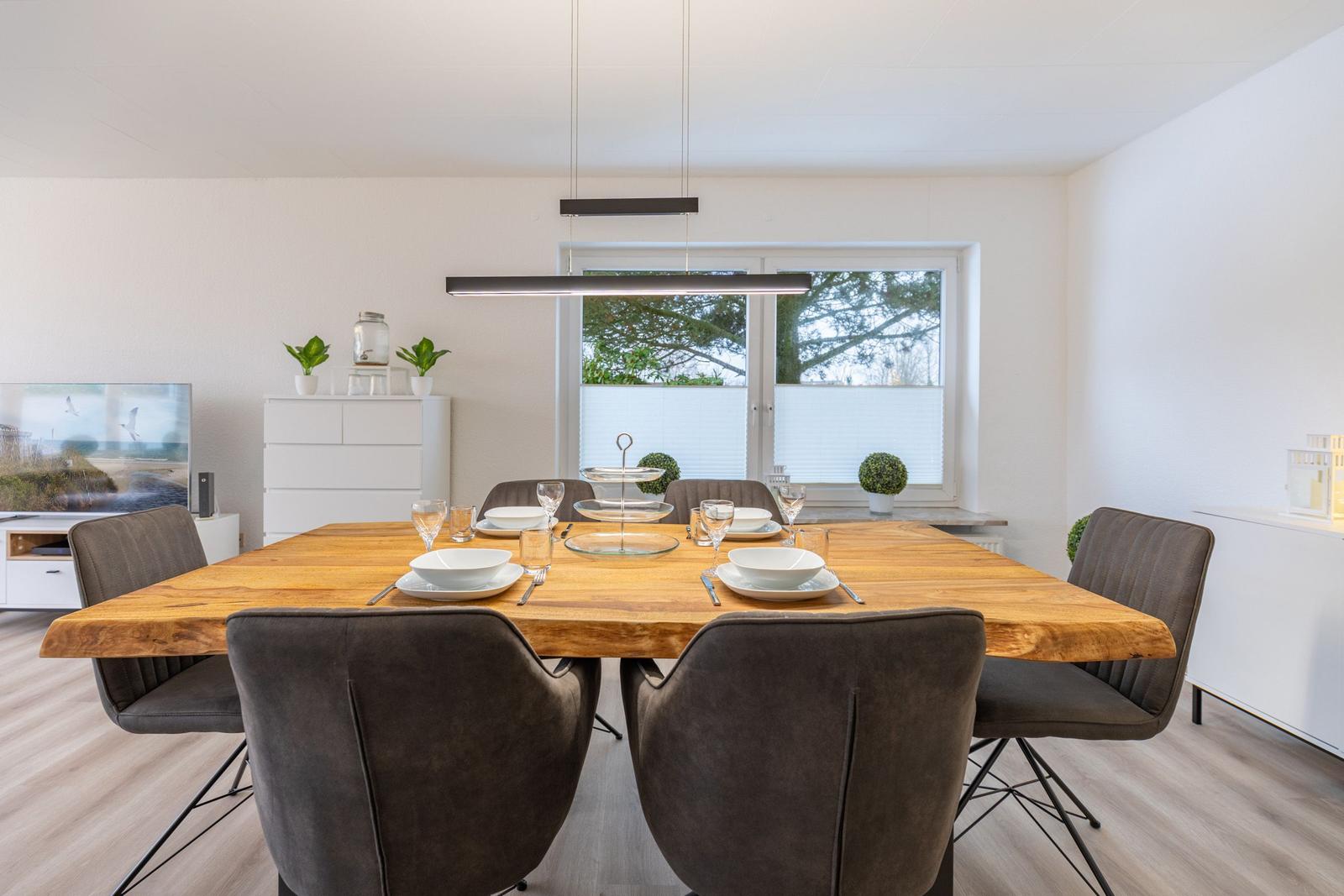 Esszimmer mit Holztisch, sechs Stühlen und Fensterblick.