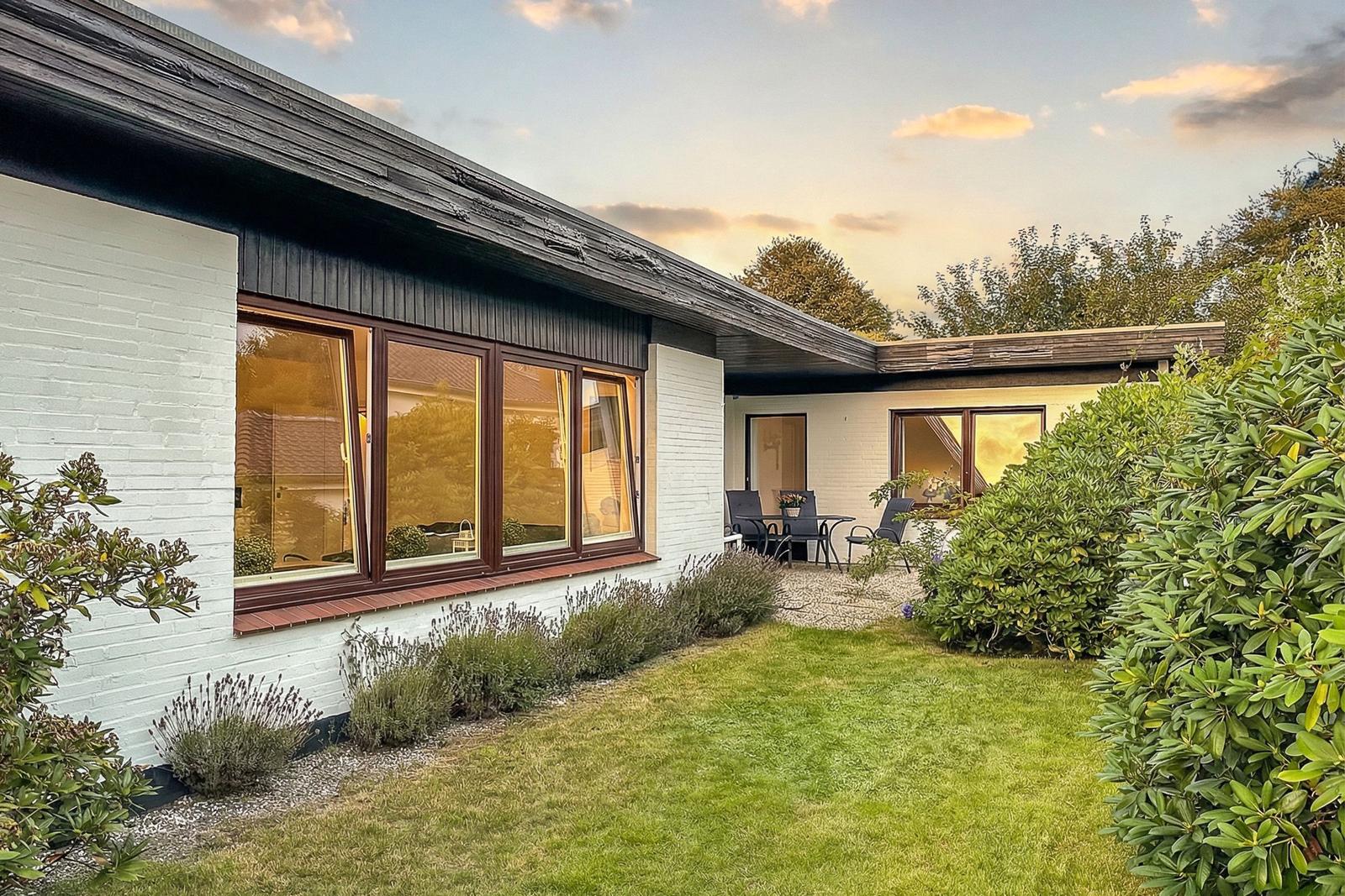 Moderne Villa mit Garten, Terrasse und Sitzgelegenheiten.