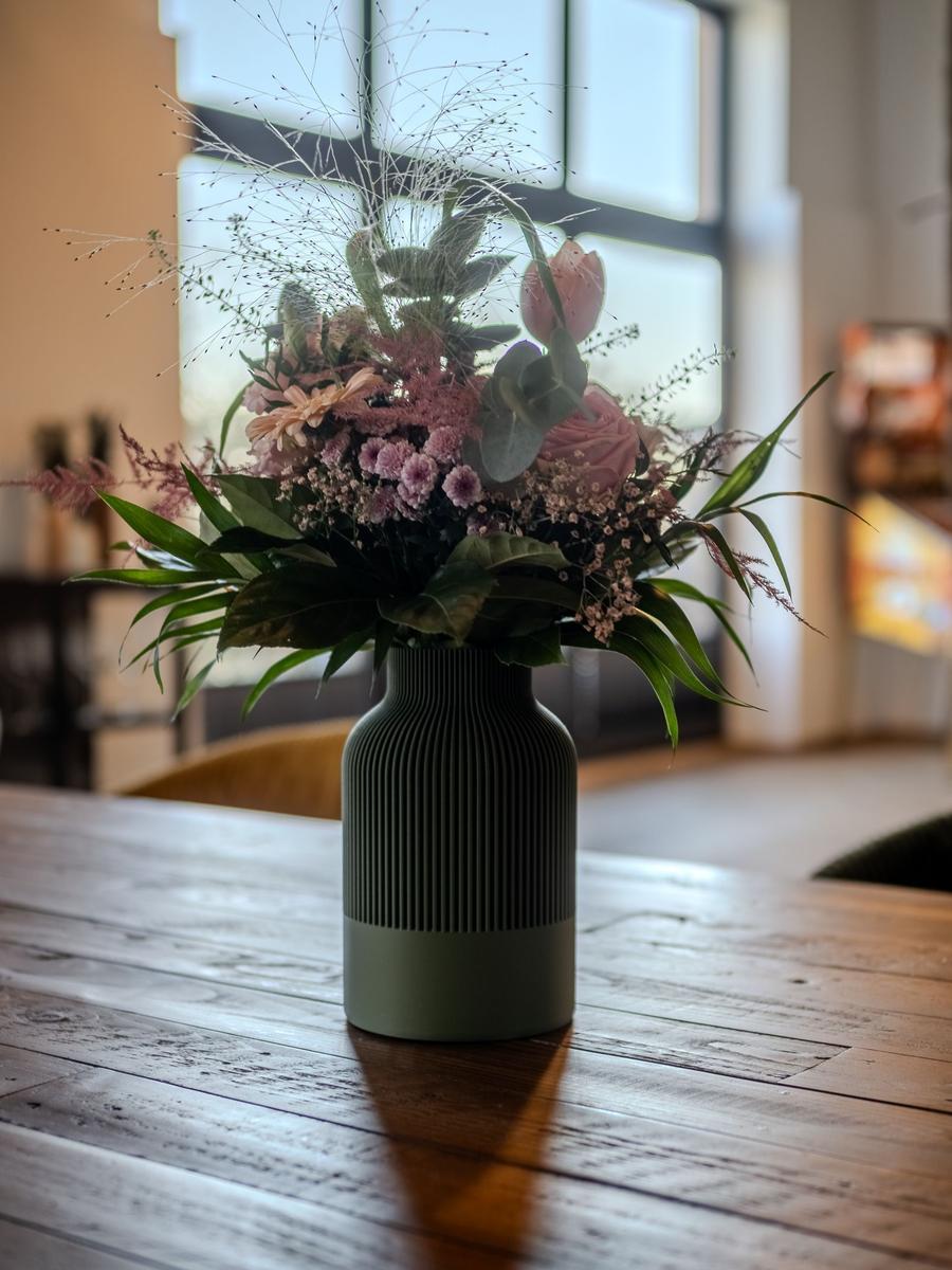Blumenstrauß in grünem Vase auf Holztisch