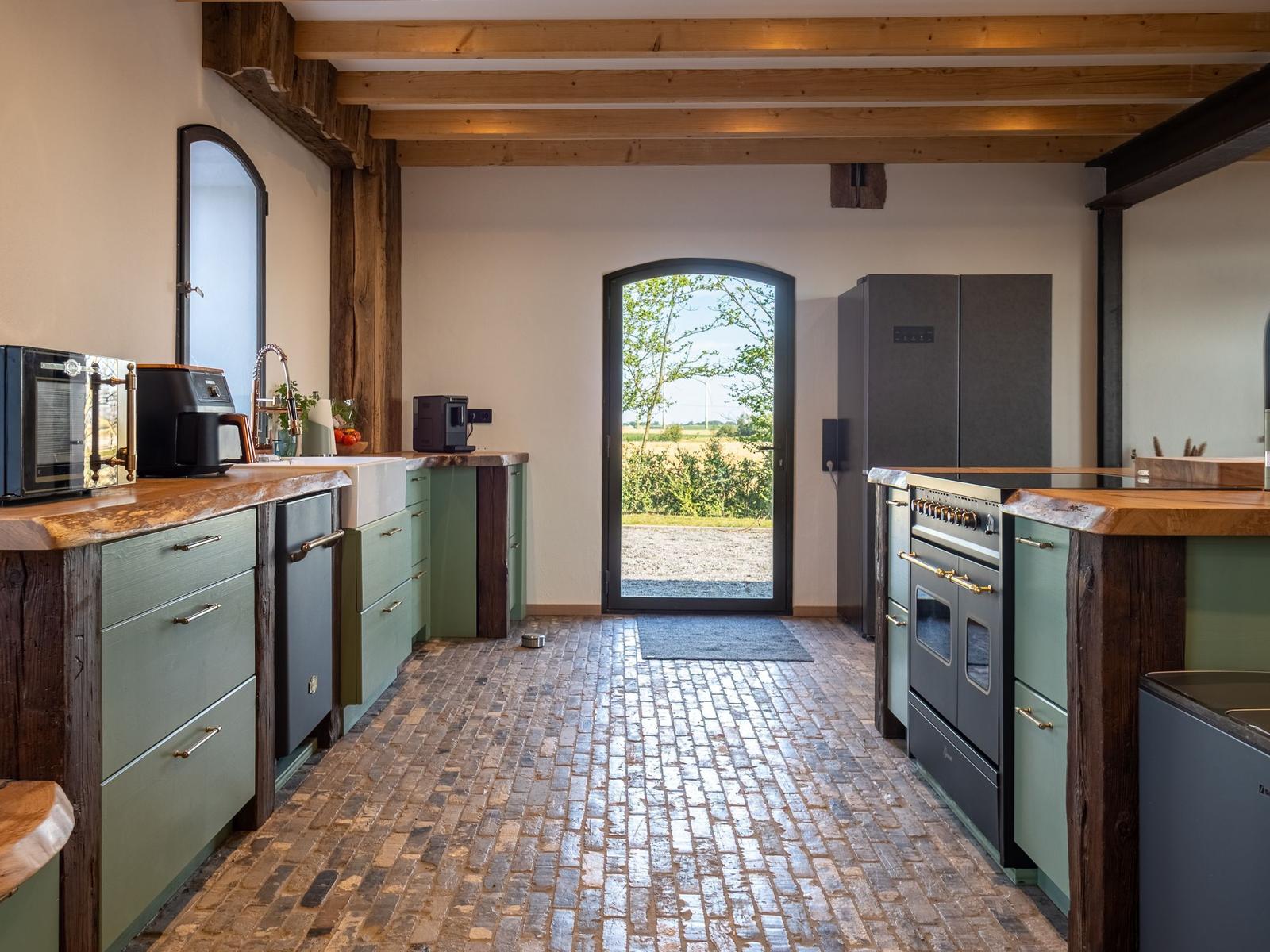 Küche mit Steinboden, Holzbalken und Blick auf Garten
