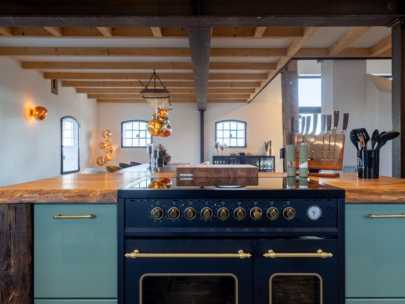 Küche mit Holzdecke, blauen Schränken und Edelstahlherd.