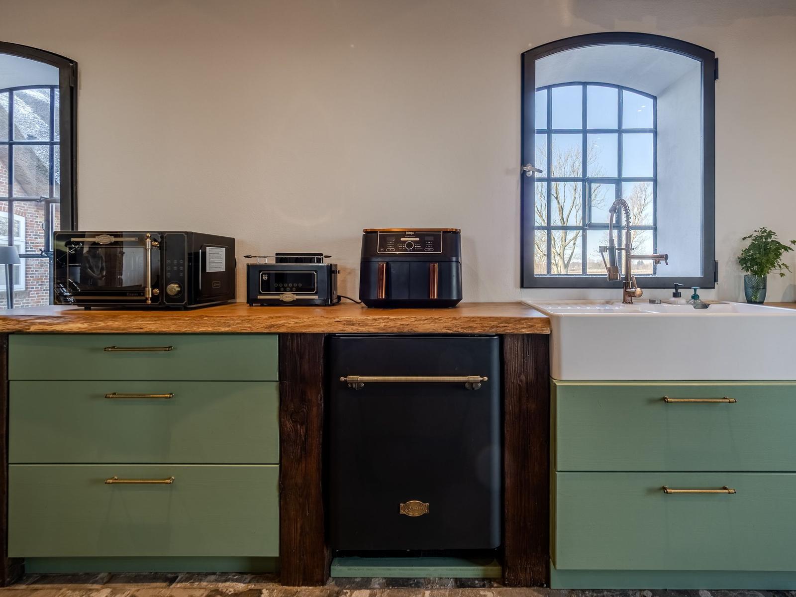 Küche mit grünen Schränken, Holzoberfläche und moderner Spüle.