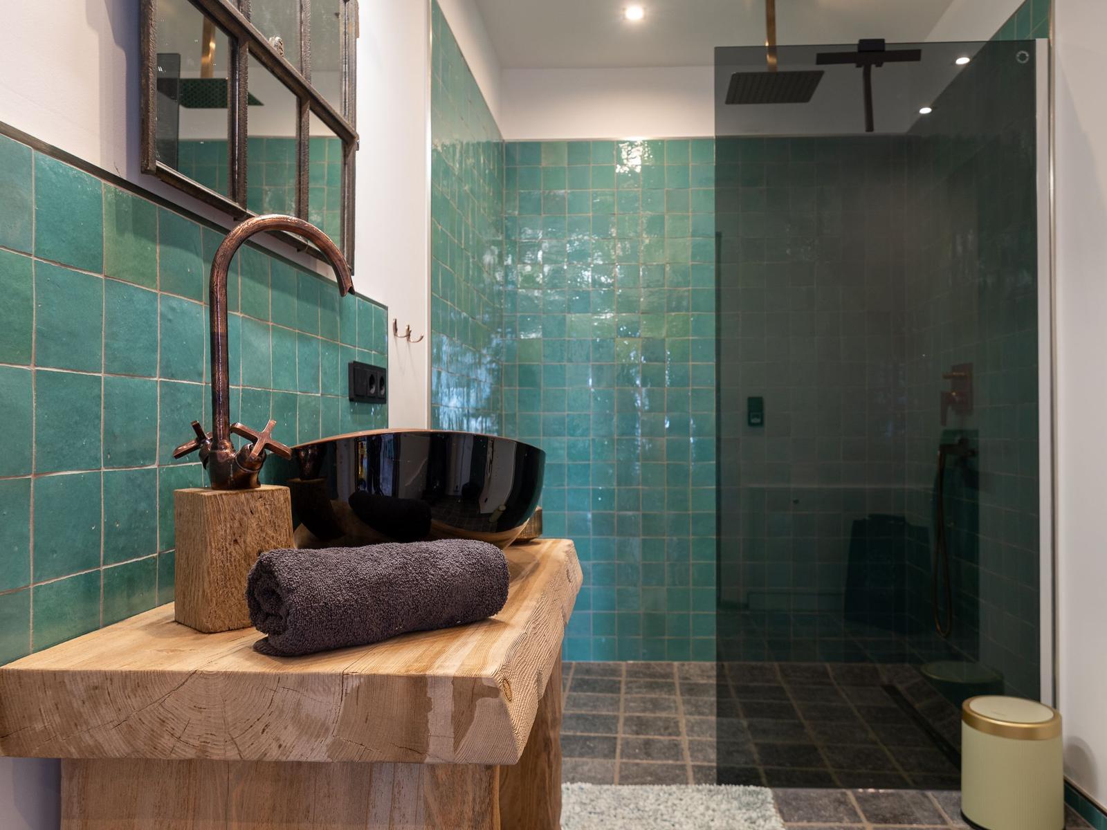 Badezimmer mit grünen Fliesen, Holzwaschtisch und Dusche