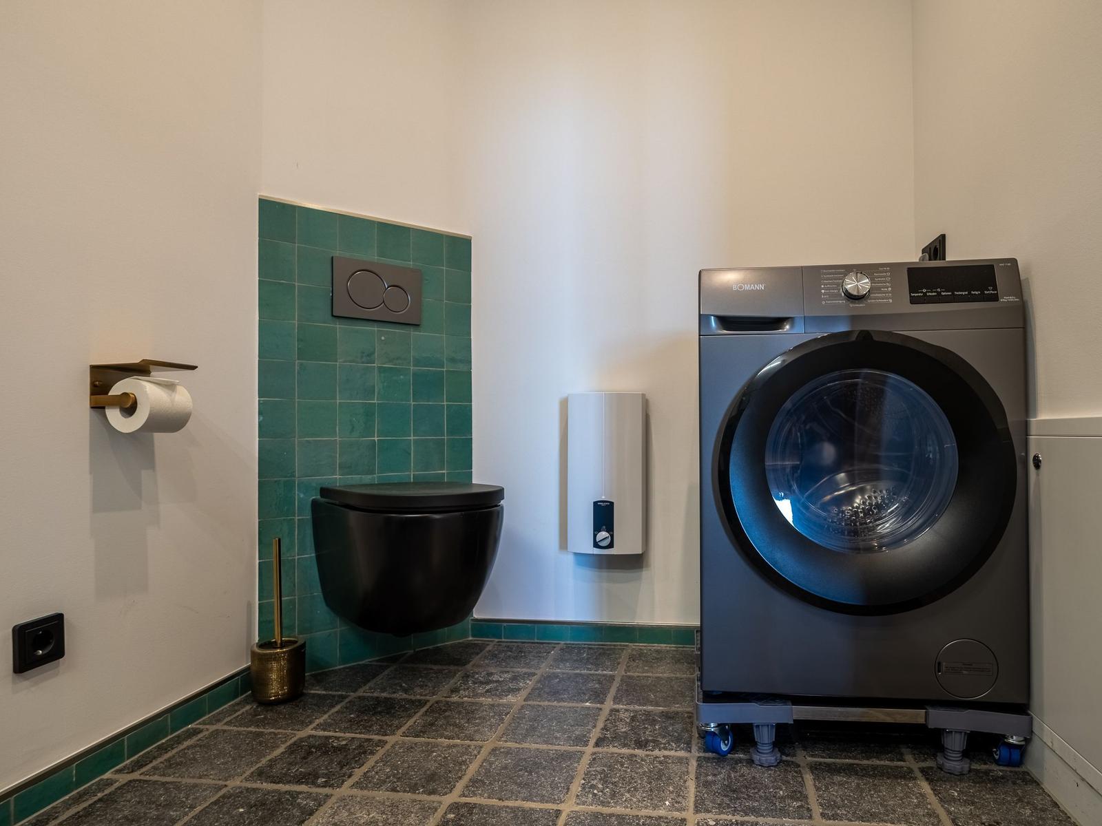 WC mit Waschmaschine und grünen Fliesen