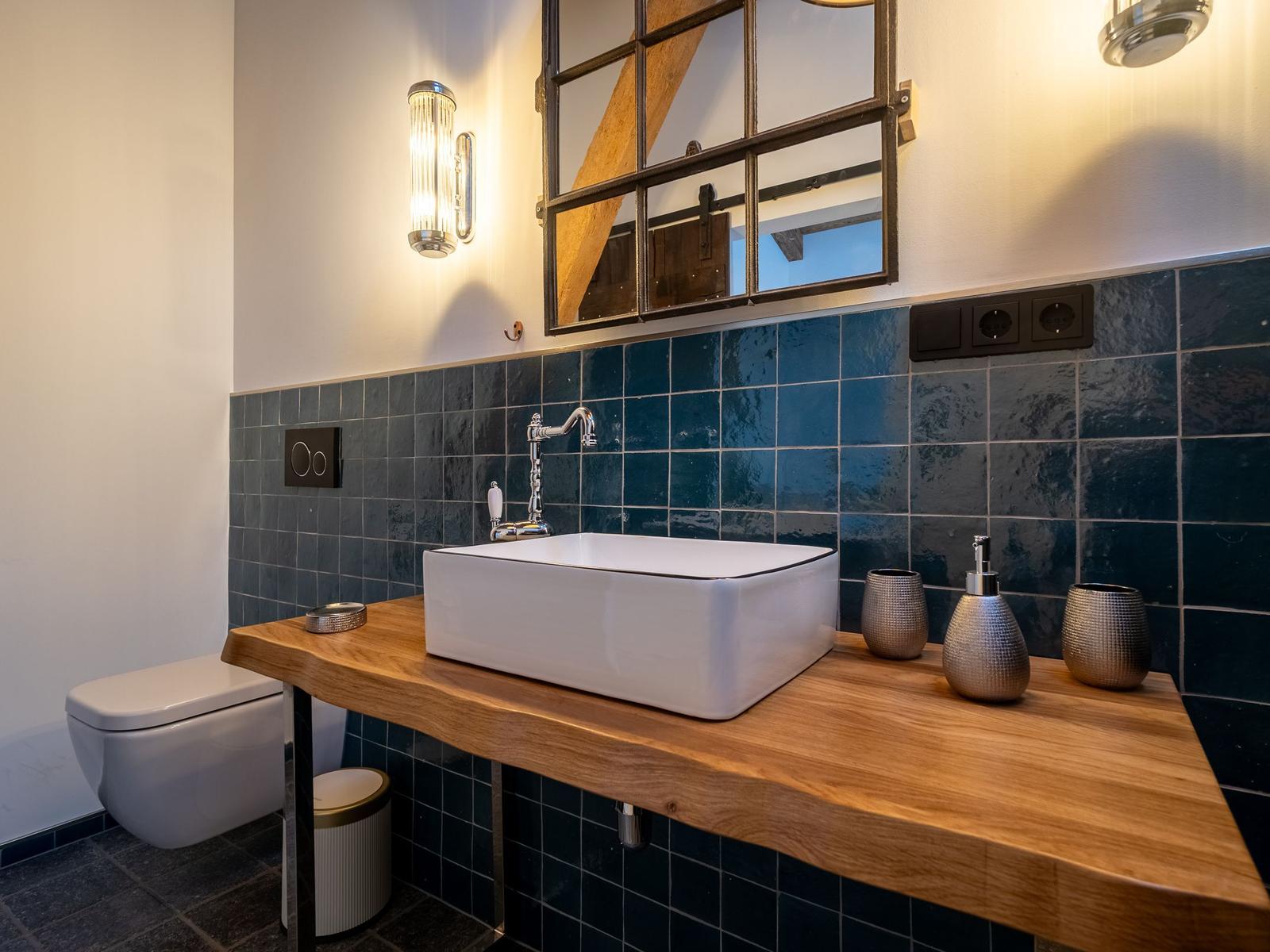 Badezimmer mit Holzwaschtisch, blauen Fliesen und Spiegel