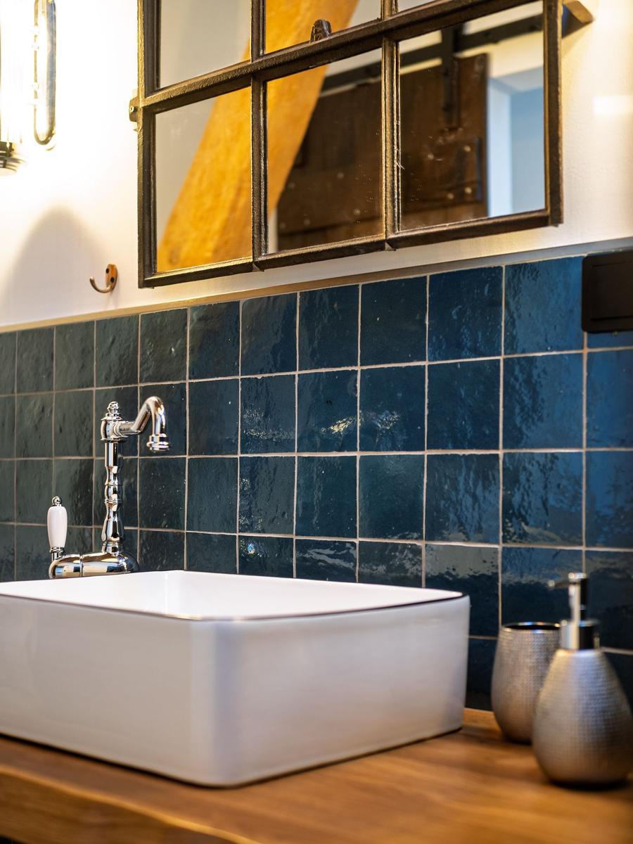 Waschbecken mit blauen Fliesen und Spiegel über dem Waschbecken.