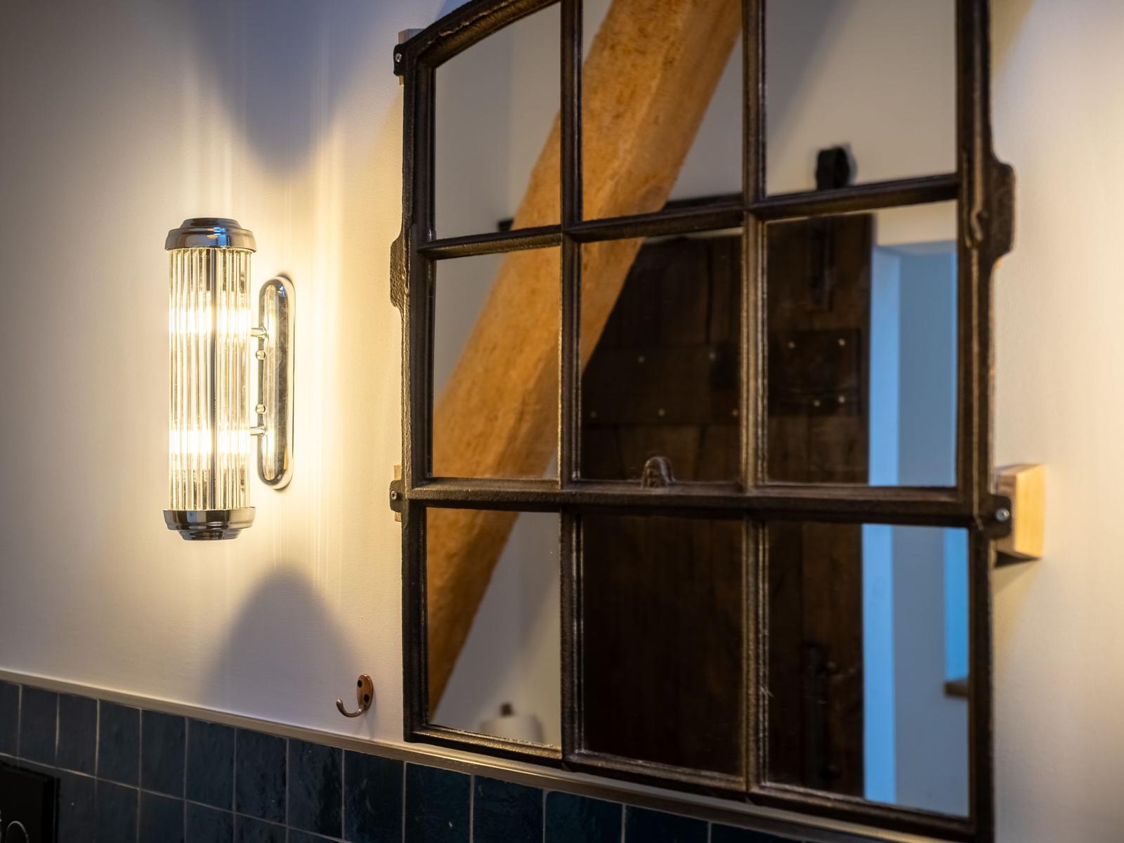 Wandlampe neben Spiegel mit Holzbalkenreflexion