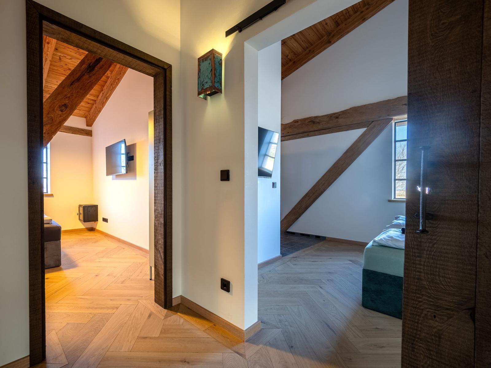 Zwei Räume mit Holzbalken, Hölzern und Fernsehern sind sichtbar.