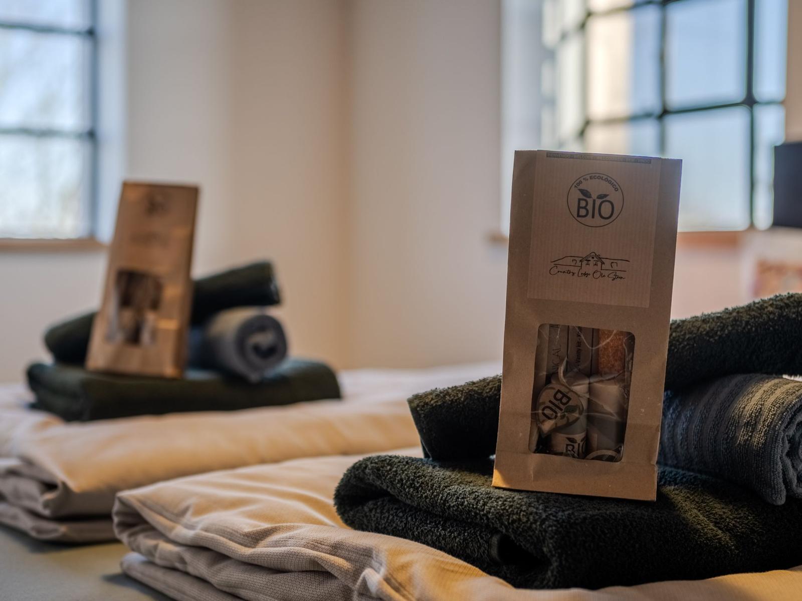 Bett mit gefalteten Handtüchern und Bio-Duschset.