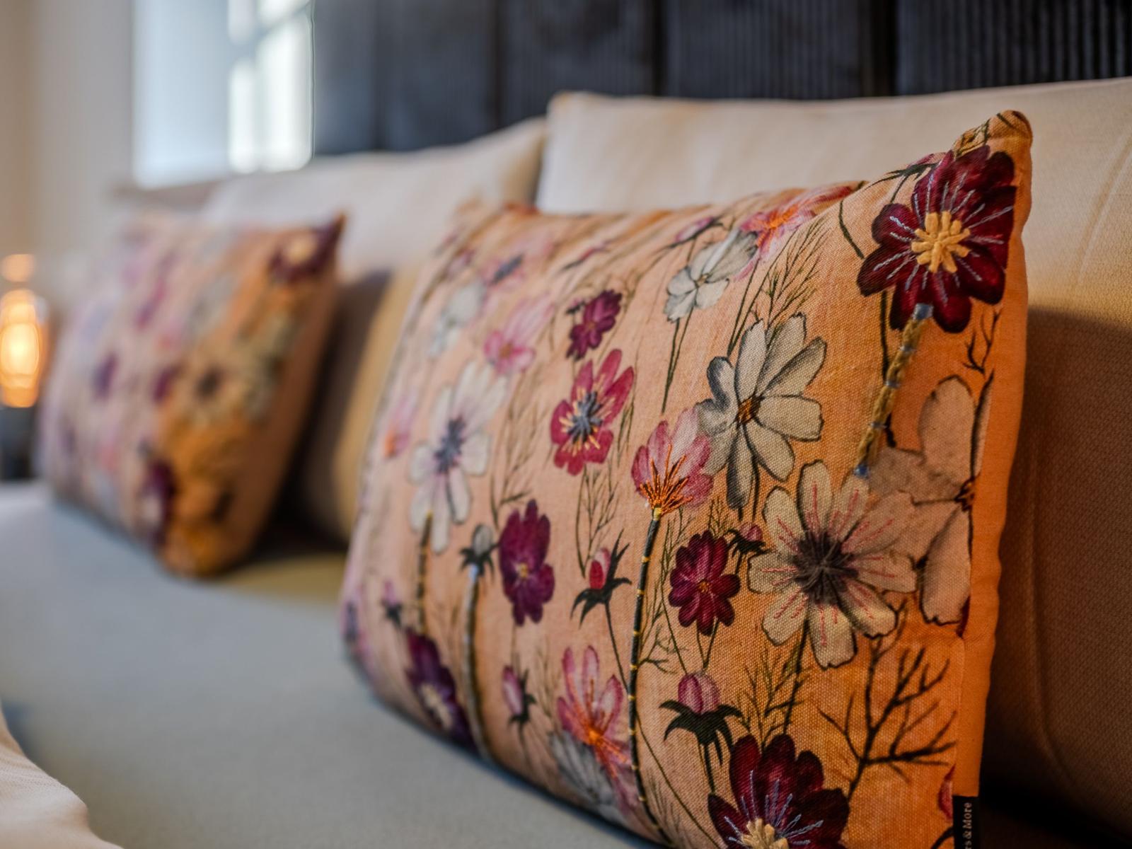 Sofa mit floralen Kissen in warmen Farbtönen.