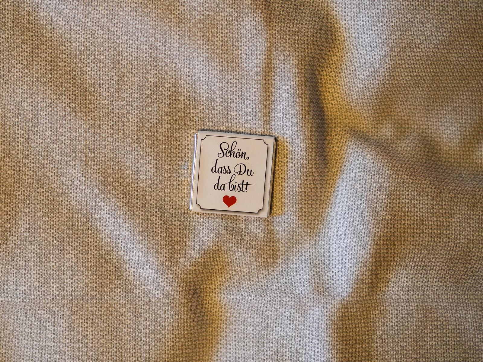 Ein kleines Schild mit der Aufschrift Schön, dass Du da bist! und einem Herzen auf Stoff.