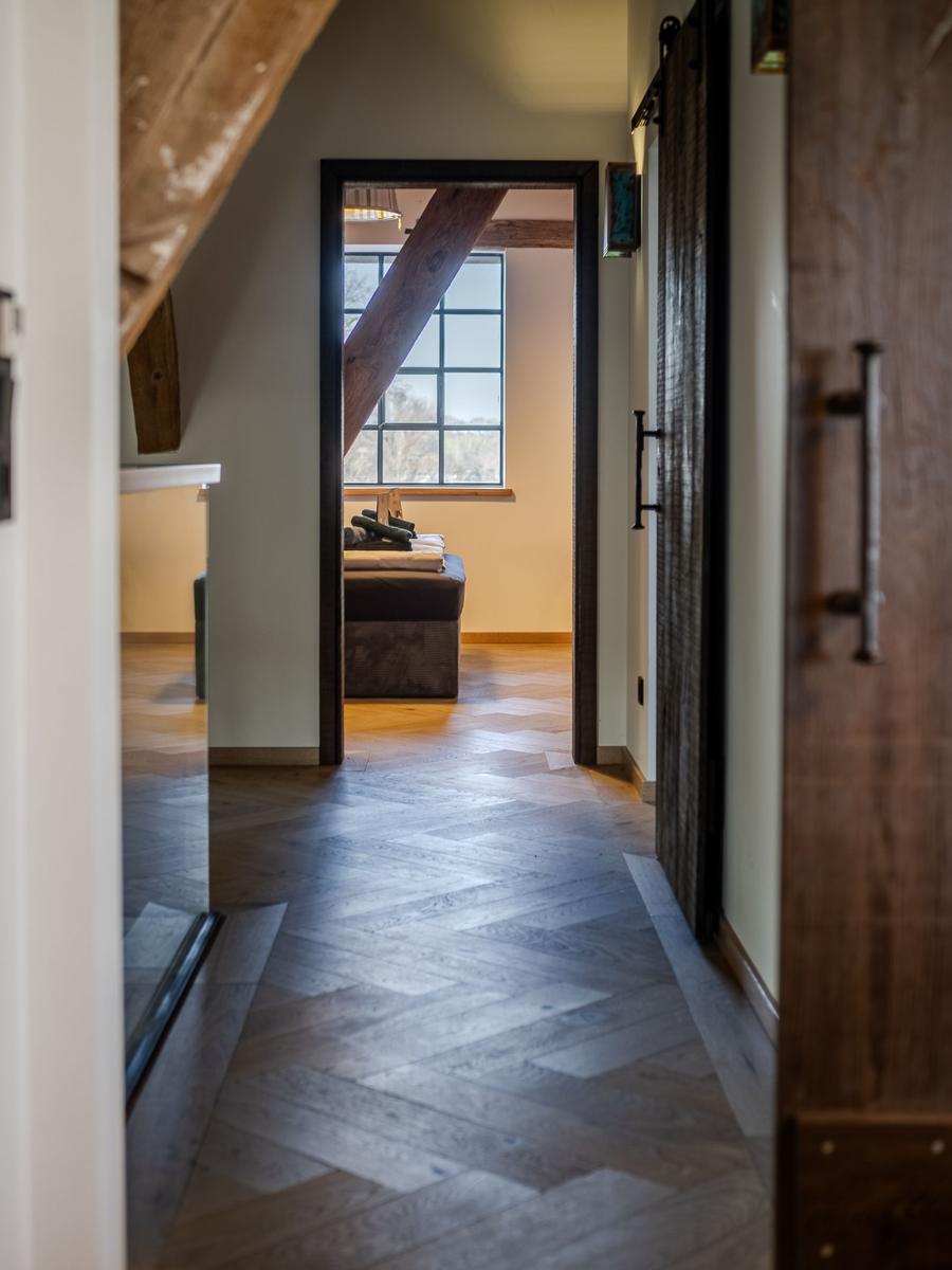 Hallenflur mit Holzboden und Blick in Schlafzimmer mit Fenster
