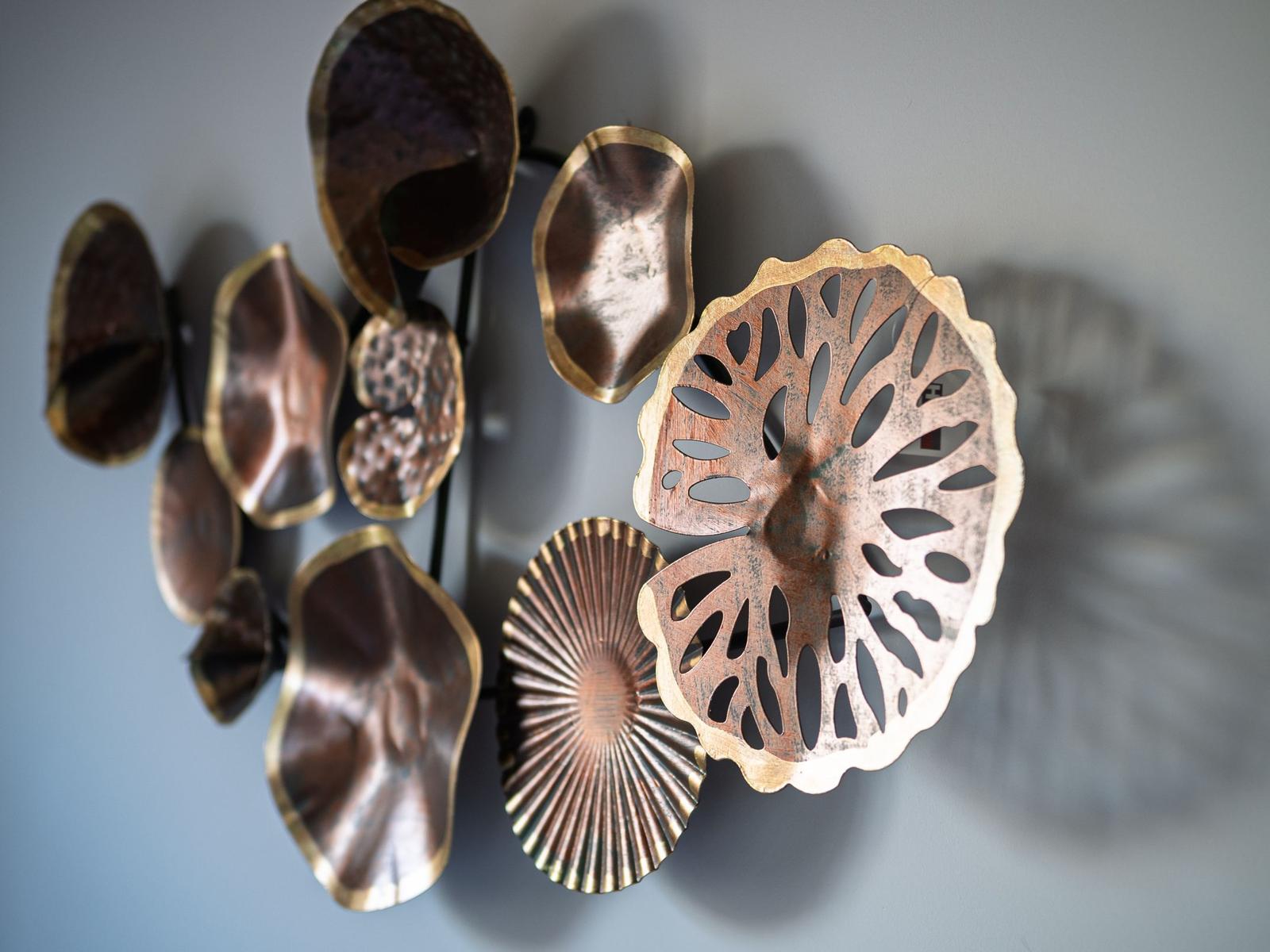 Metallkunstwerk an der Wand mit blätterförmigen Elementen.