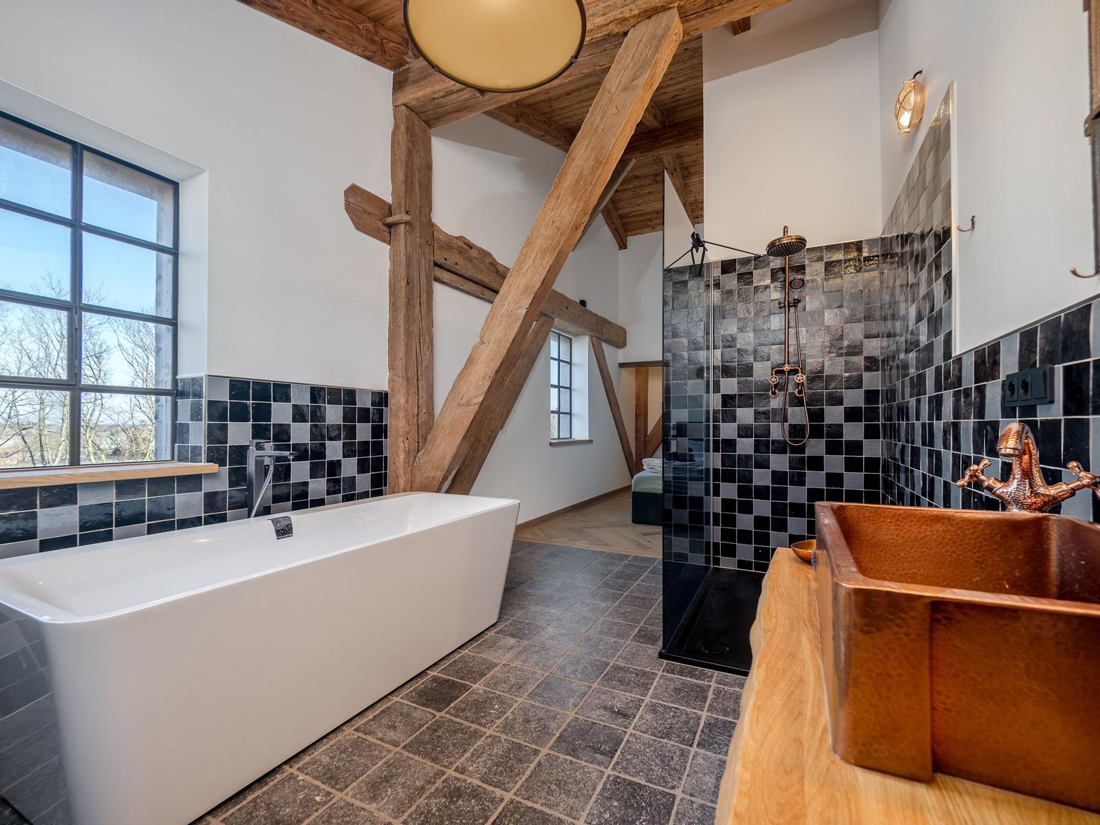 Badezimmer mit freistehender Badewanne, Dusche und Holzkonstruktion.