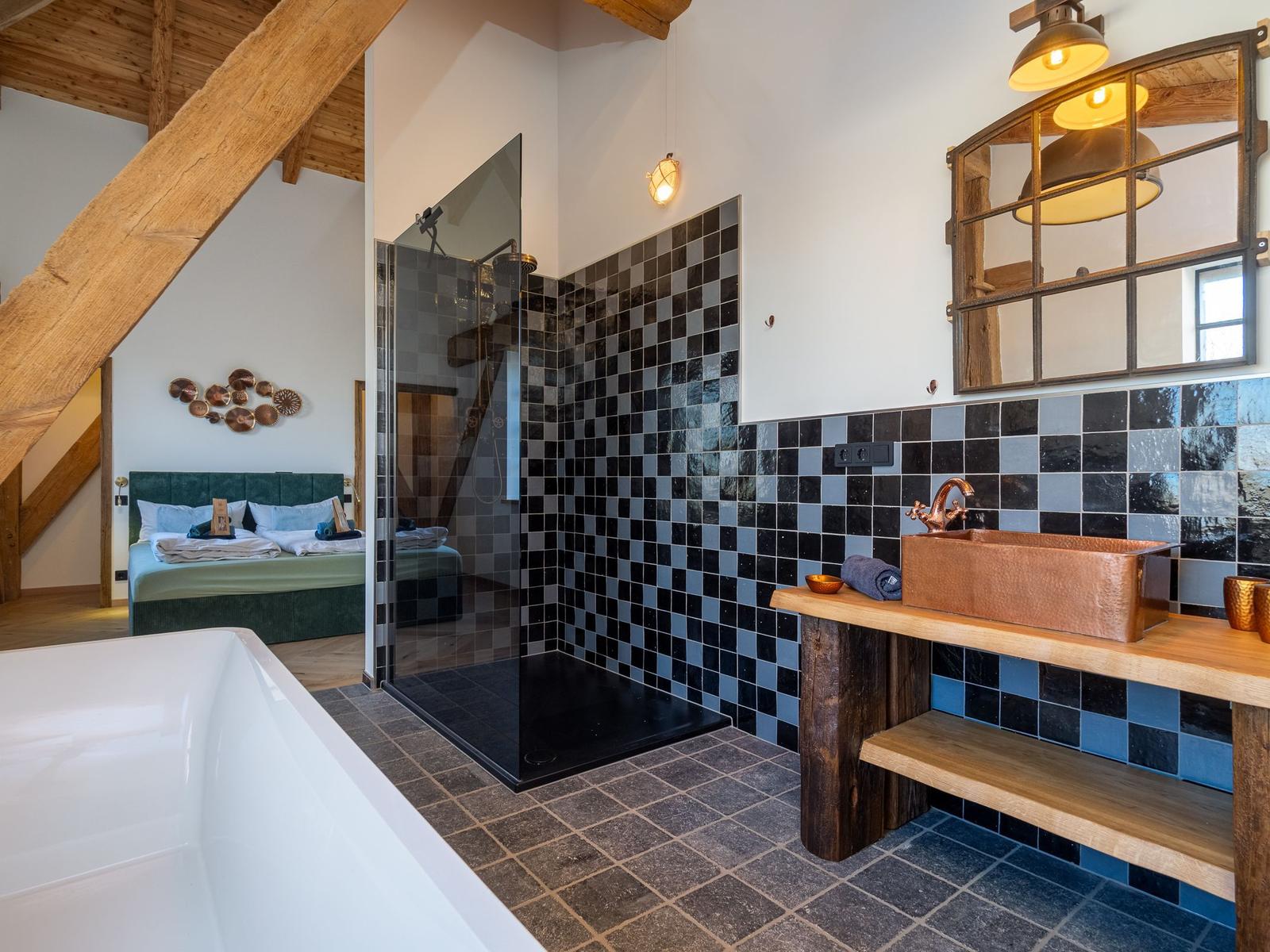 Badezimmer mit Dusche, Badewanne und Waschtisch. Holzdecken und Fliesenwand.