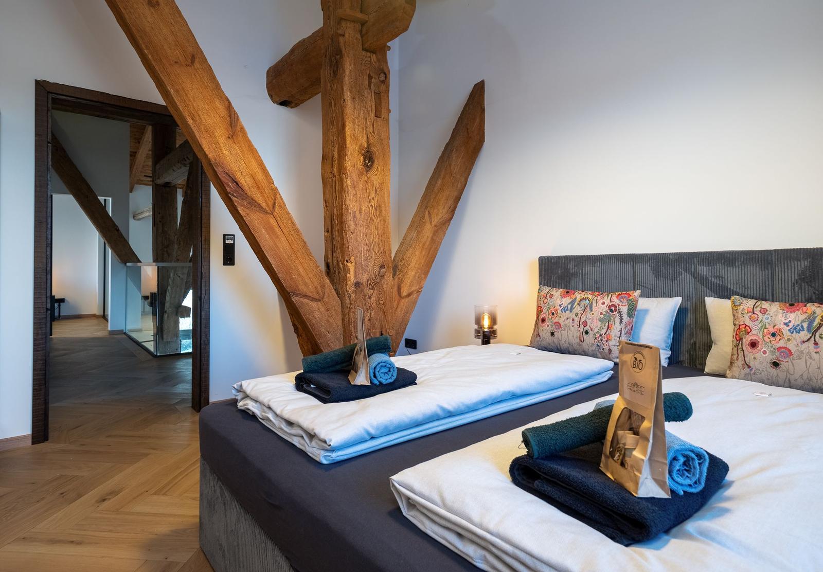 Schlafzimmer mit massivem Holzgestell und Bett mit Kissen.