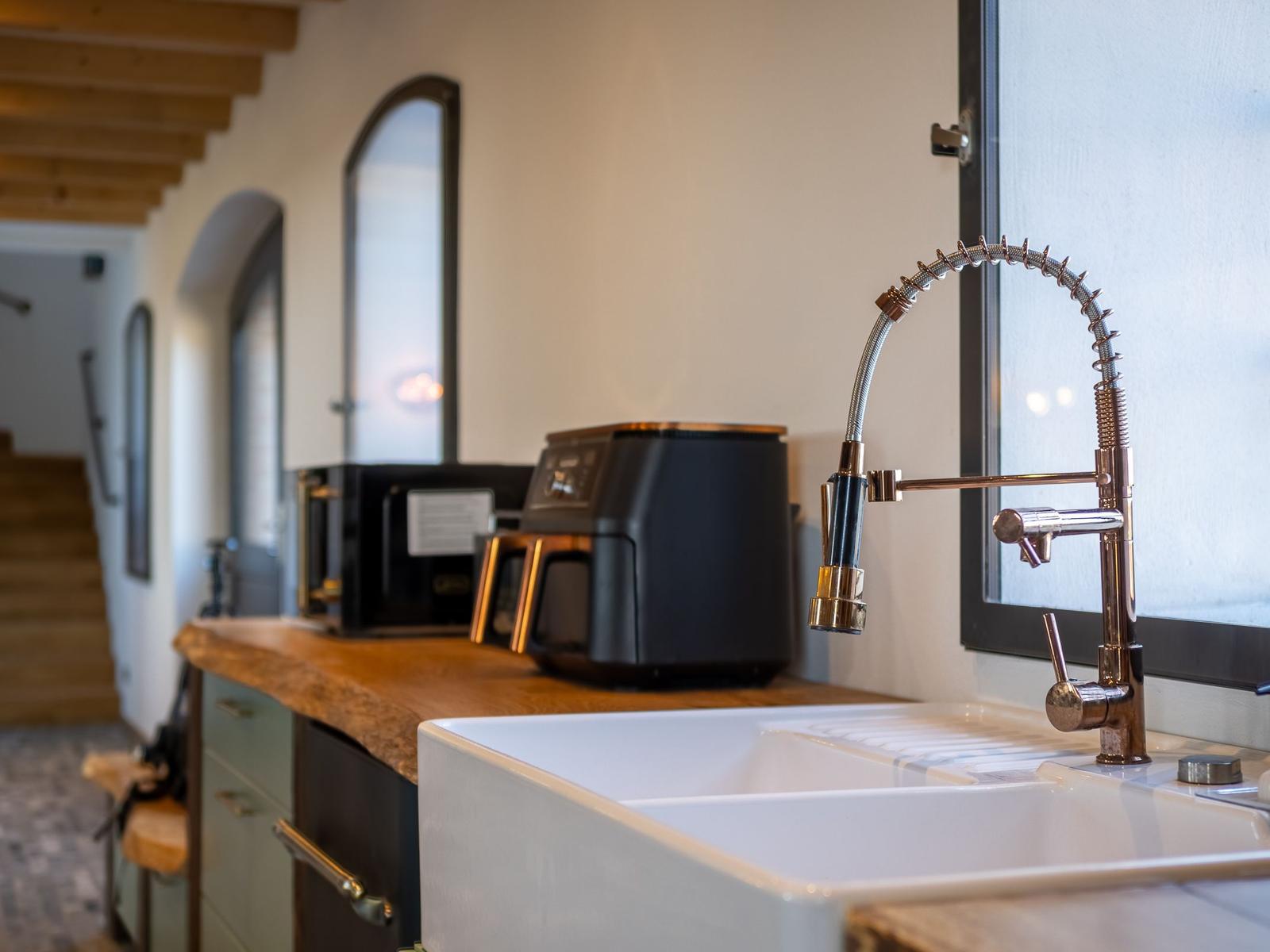 Küche mit großer Spüle, modernem Wasserhahn und Küchengeräten.