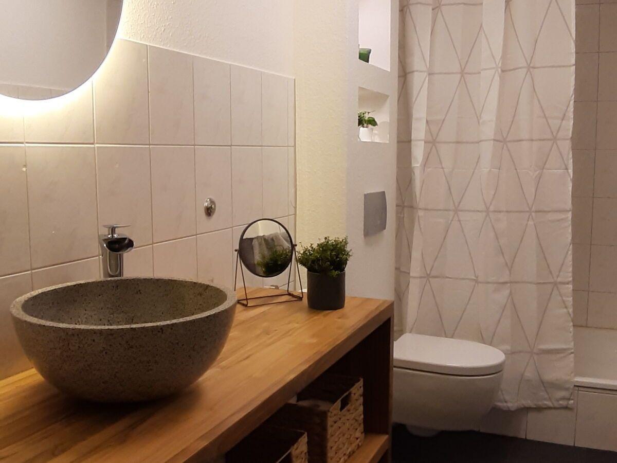 Bathroom with basin on wood, toilet, and shower curtain.