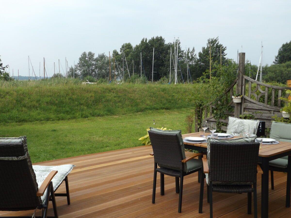 Deck with table and chairs, view of grassland and sailboats