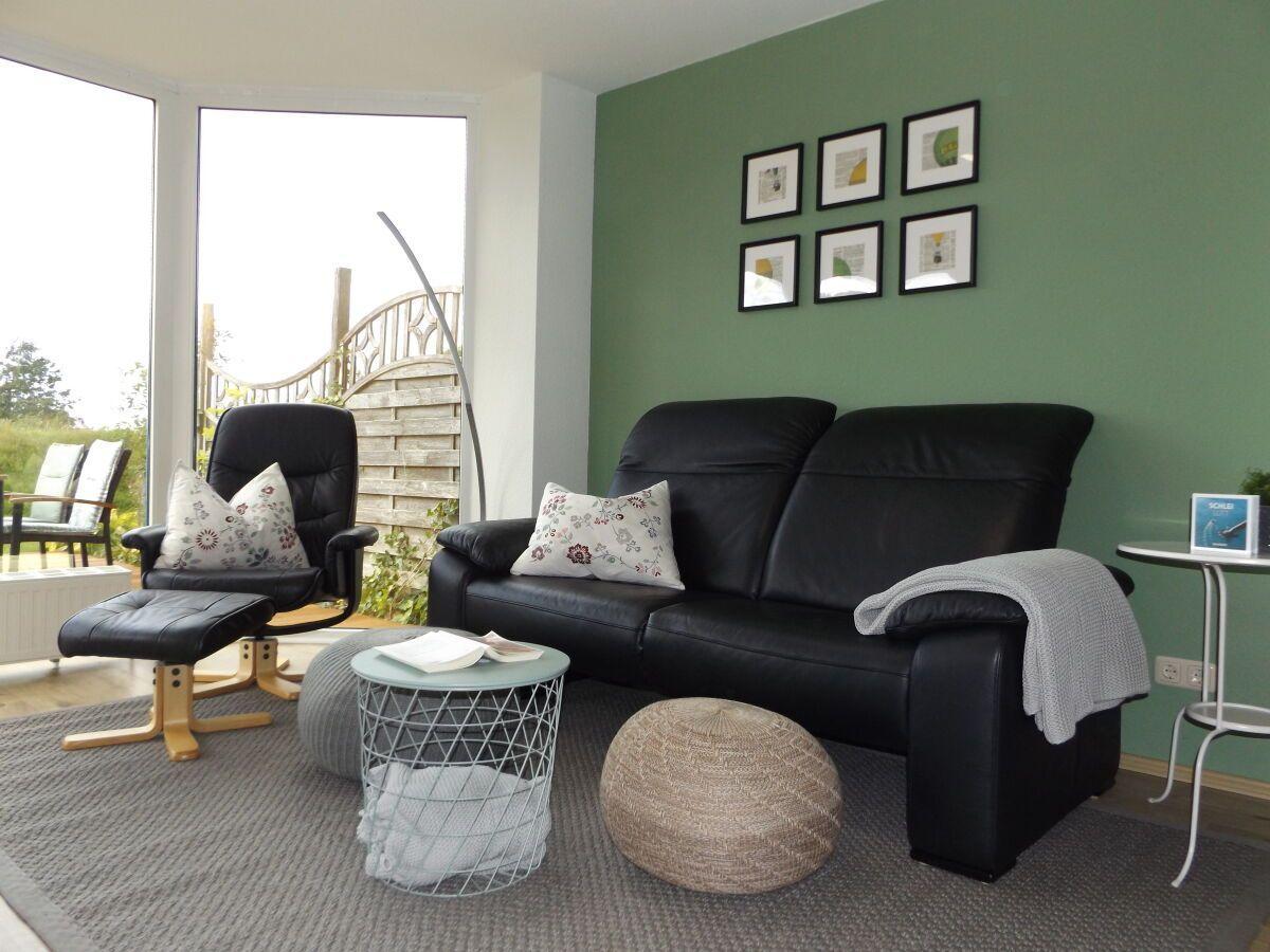 Living room with black leather sofa, seating area, and view to terrace.
