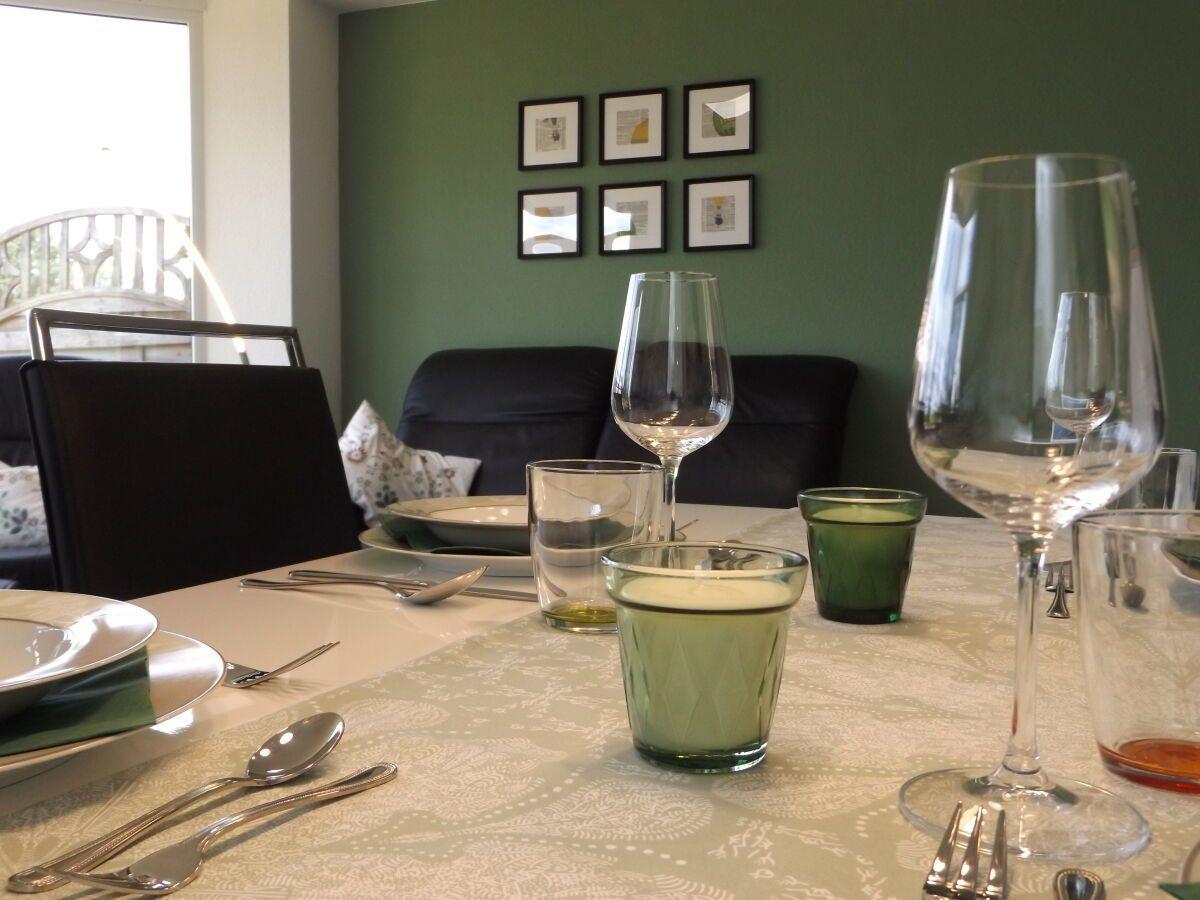 Dining table with dishes and glasses against green wall with pictures.
