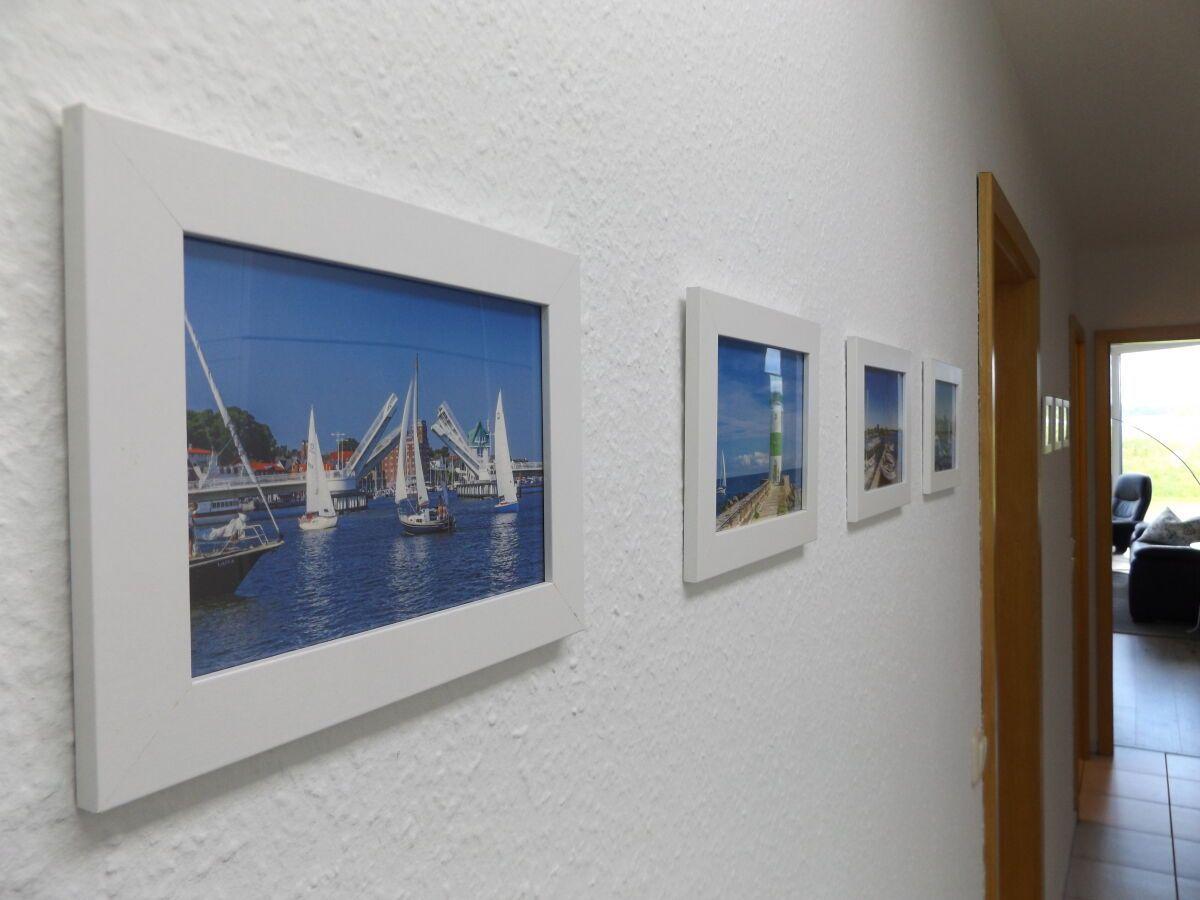 Wall with four framed pictures of sailboats and coastal landscapes.