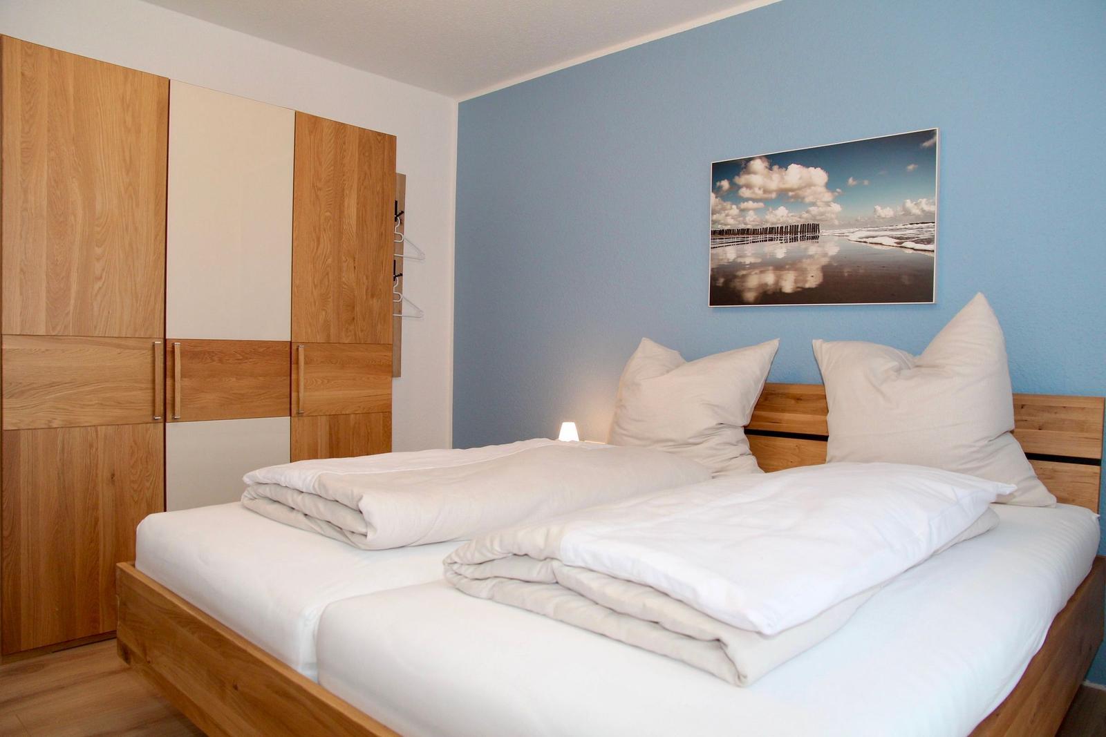 Schlafzimmer mit Doppelbett, Holzmöbel und Wandbild