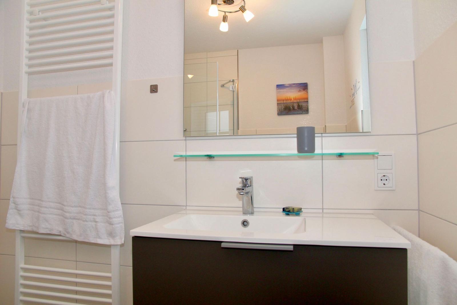 Badezimmer mit Waschbecken, Spiegel und Handtuchhalter.