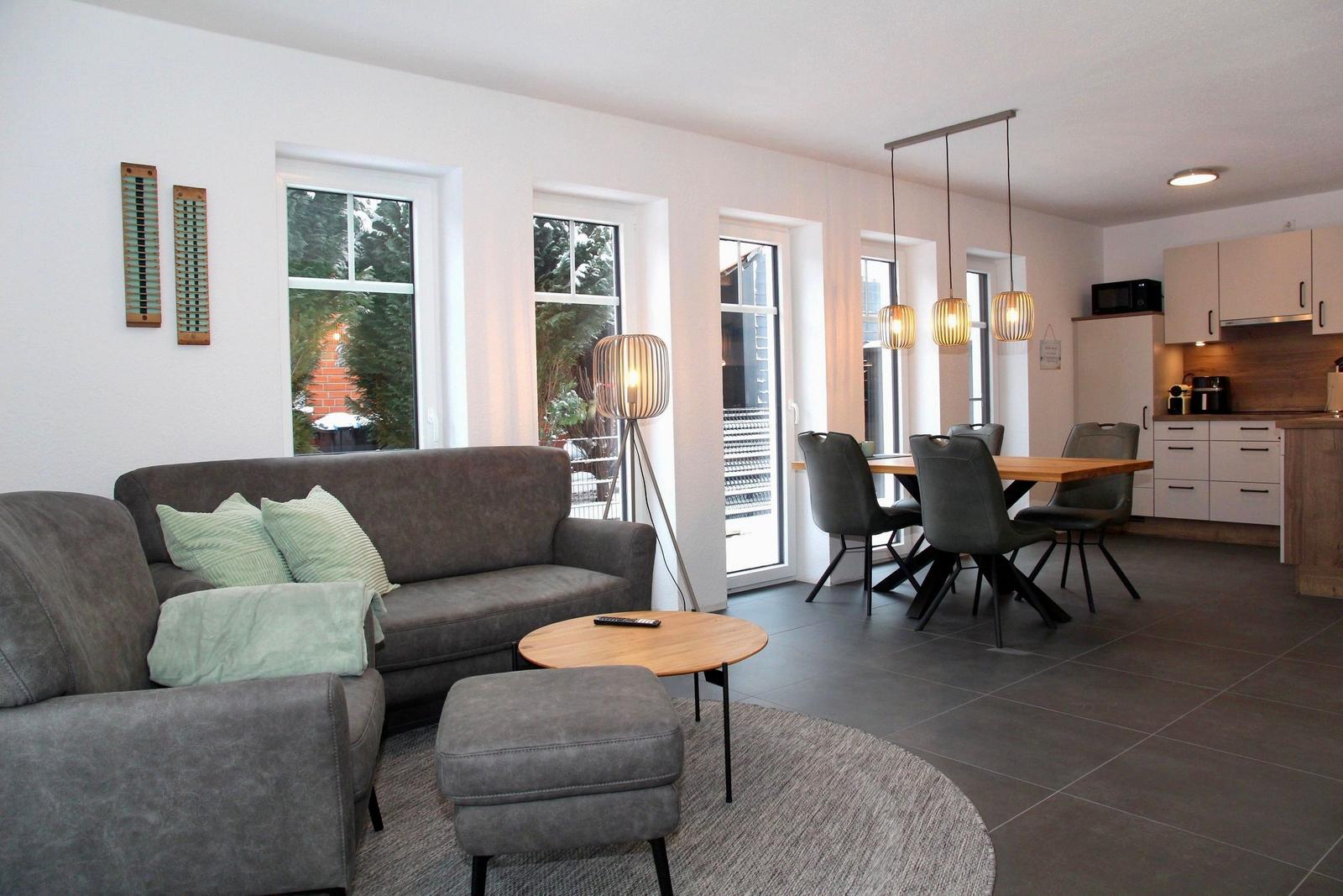 Wohn- und Essbereich mit Sofa, Tisch und Küchenzeile.