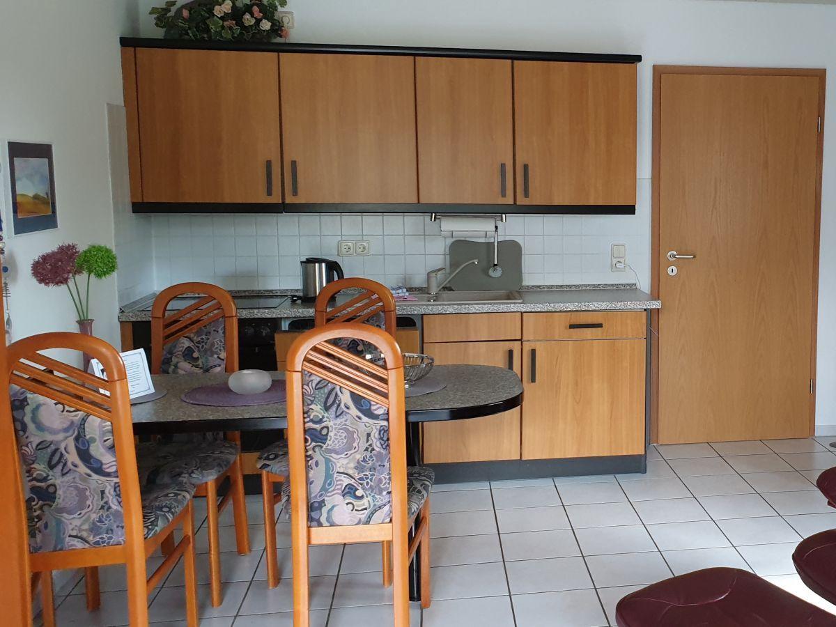 Küche mit Esstisch, Holzschränken und Fliesenboden.