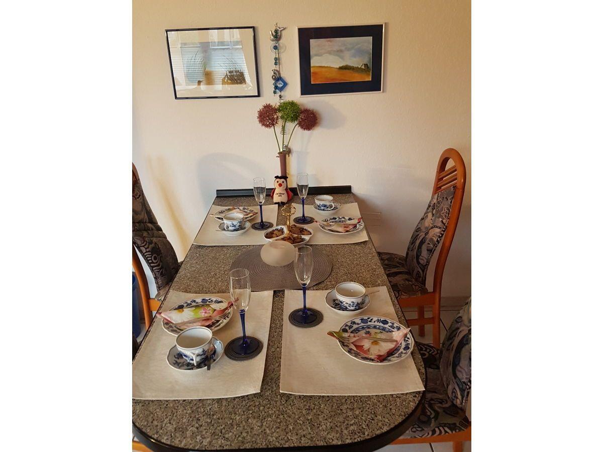 Gestellte Tischdecke mit Tassen, Gläsern und Blumen auf Tisch