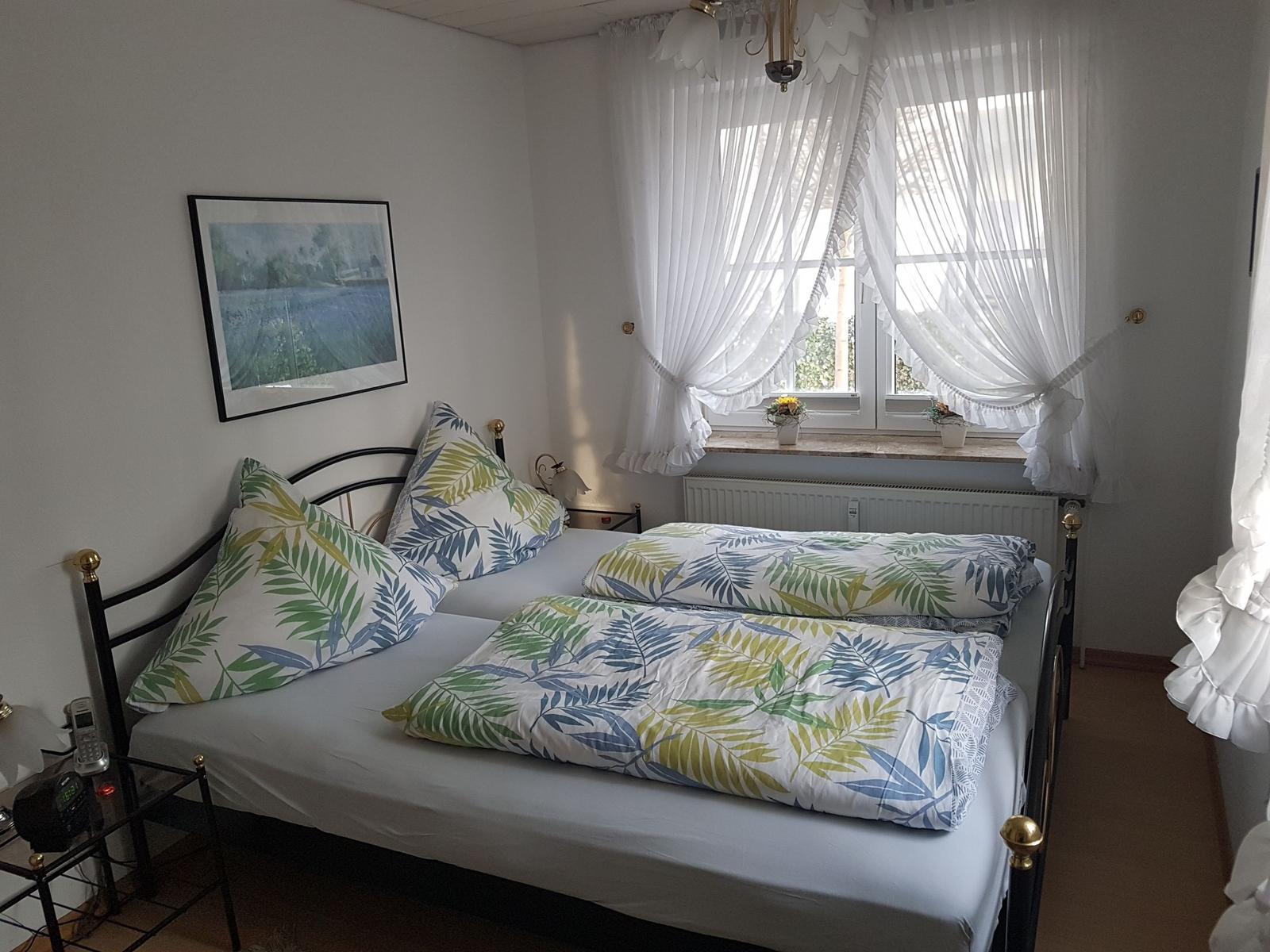 Schlafzimmer mit Bett, Fenster und Wandbild