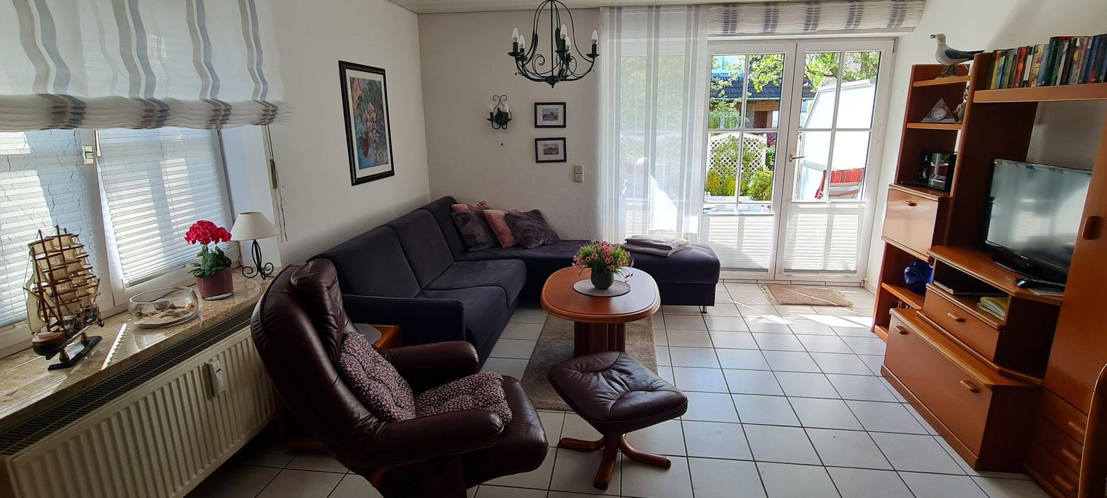 Wohnzimmer mit Sofa, Sessel und TV-Möbel. Durchgang zur Terrasse.