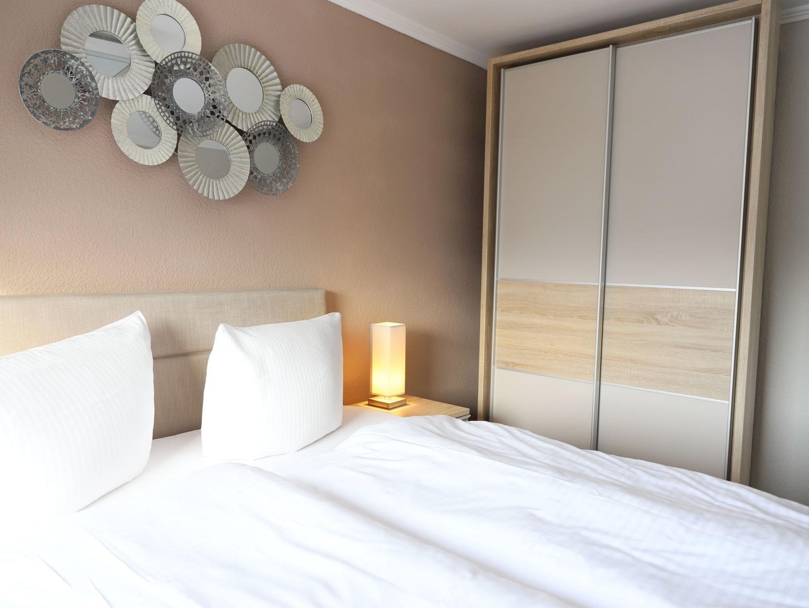 Schlafzimmer mit Bett, Nachttisch und Kleiderschrank.