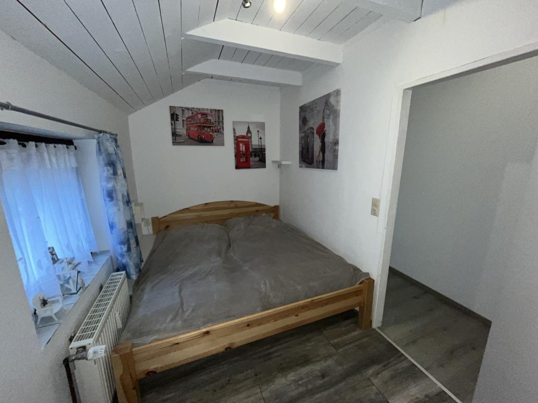 Bedroom with wooden bed, wall art, and window with curtains.
