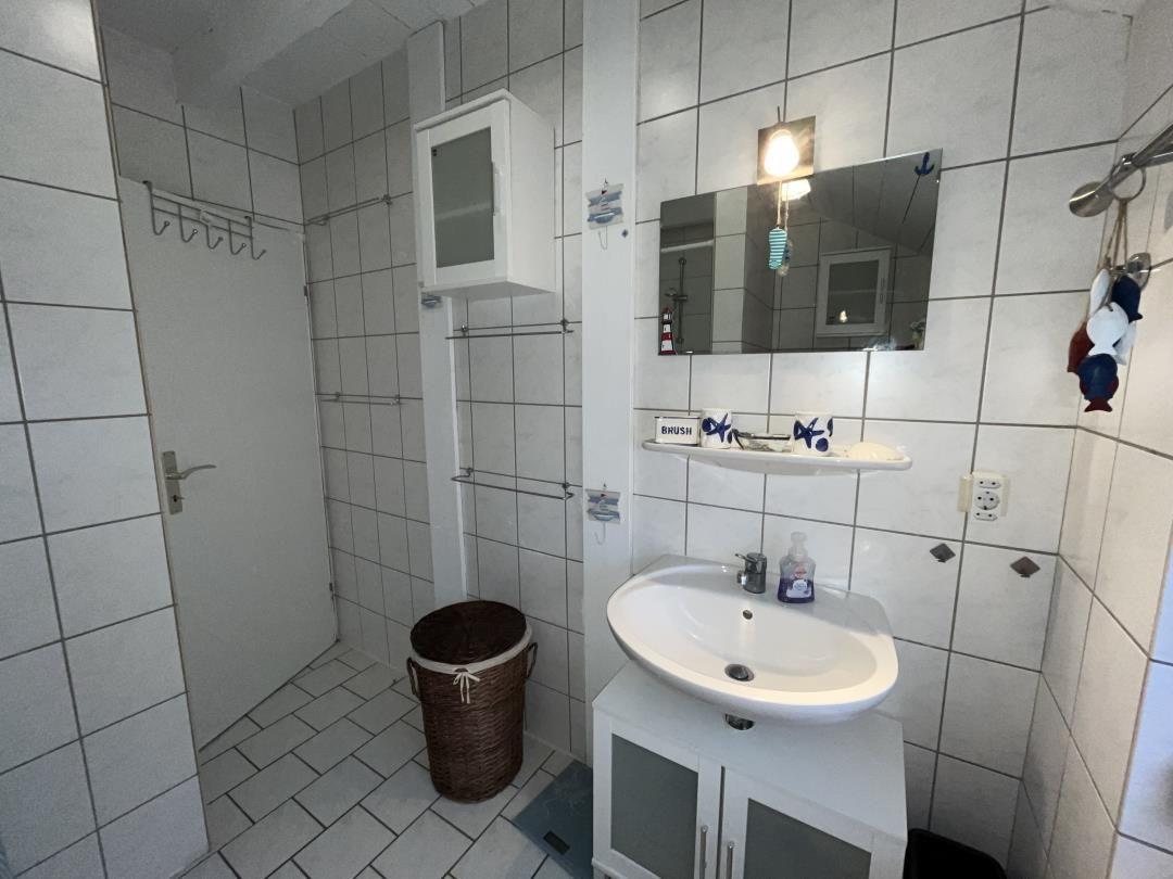 Bathroom with sink, mirror, and shower.