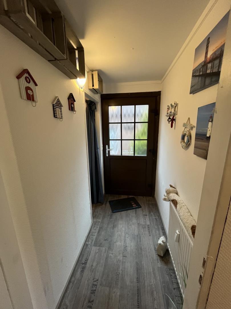 Hallway with wooden floor, door, and wall pictures