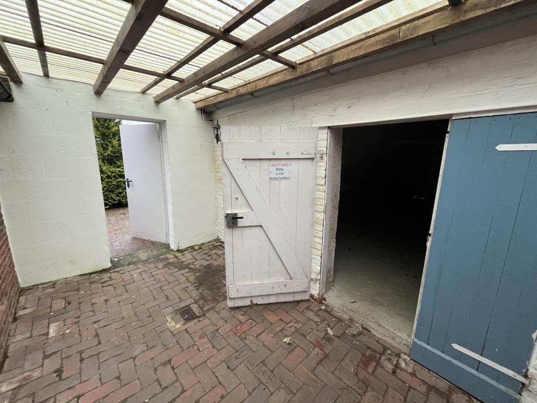 Backyard with gate, garage door, and roof structure of wood and glass.