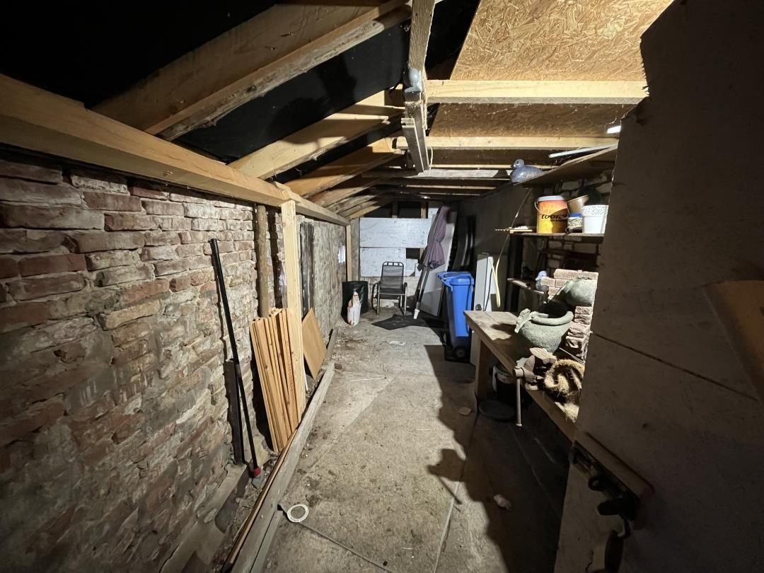Attic with stone wall, wooden beams, and tools