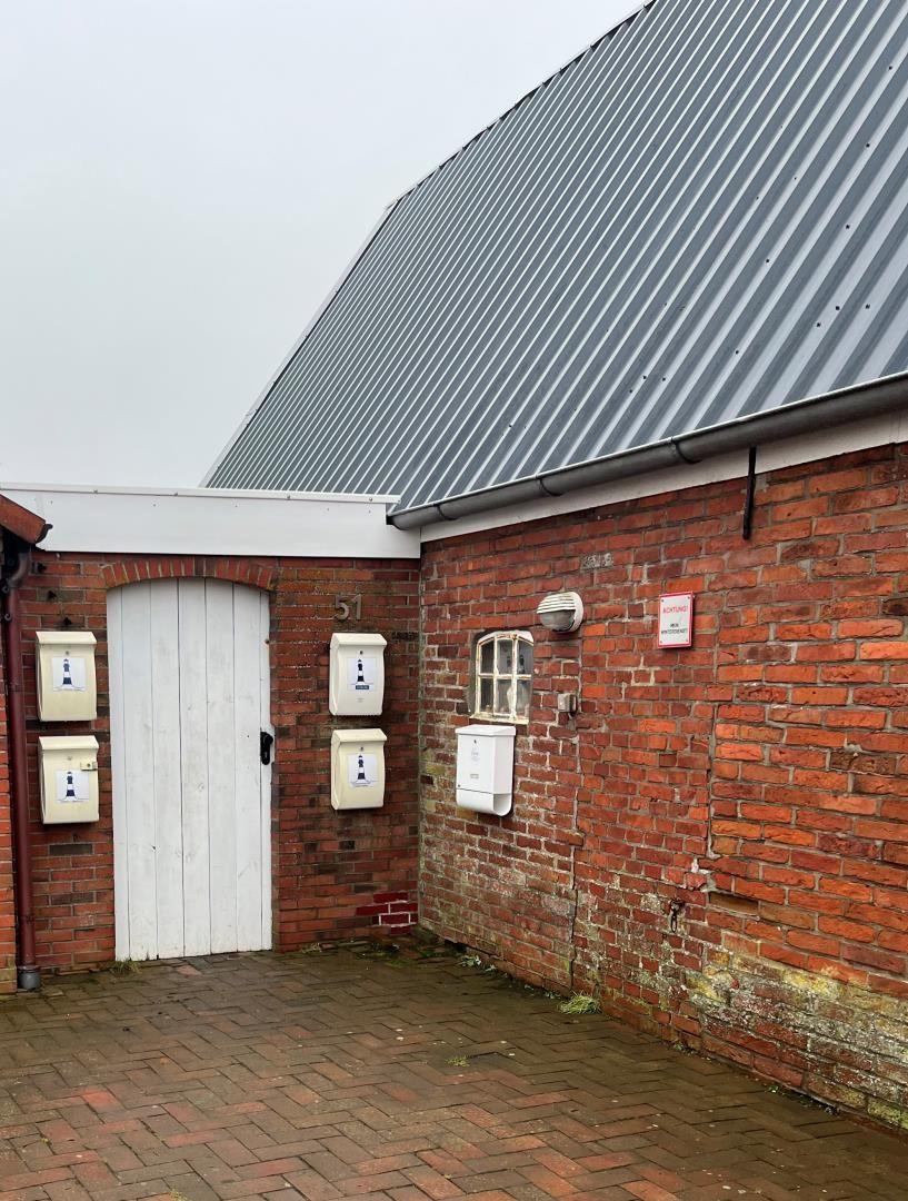 Red brick building with white mailboxes and sloped metal roof.