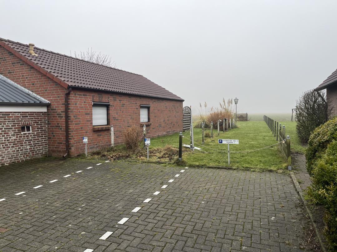 House with stone wall, paved yard, and green lawn area.