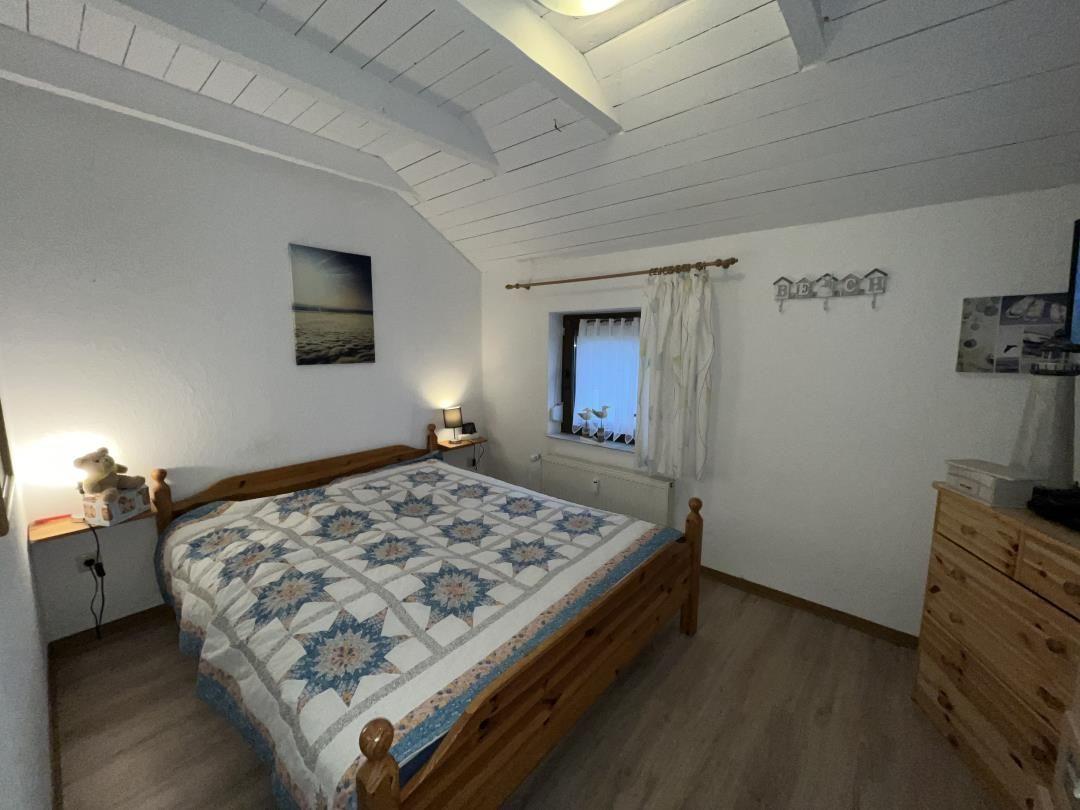 Bedroom with wooden bed, window, and dresser.