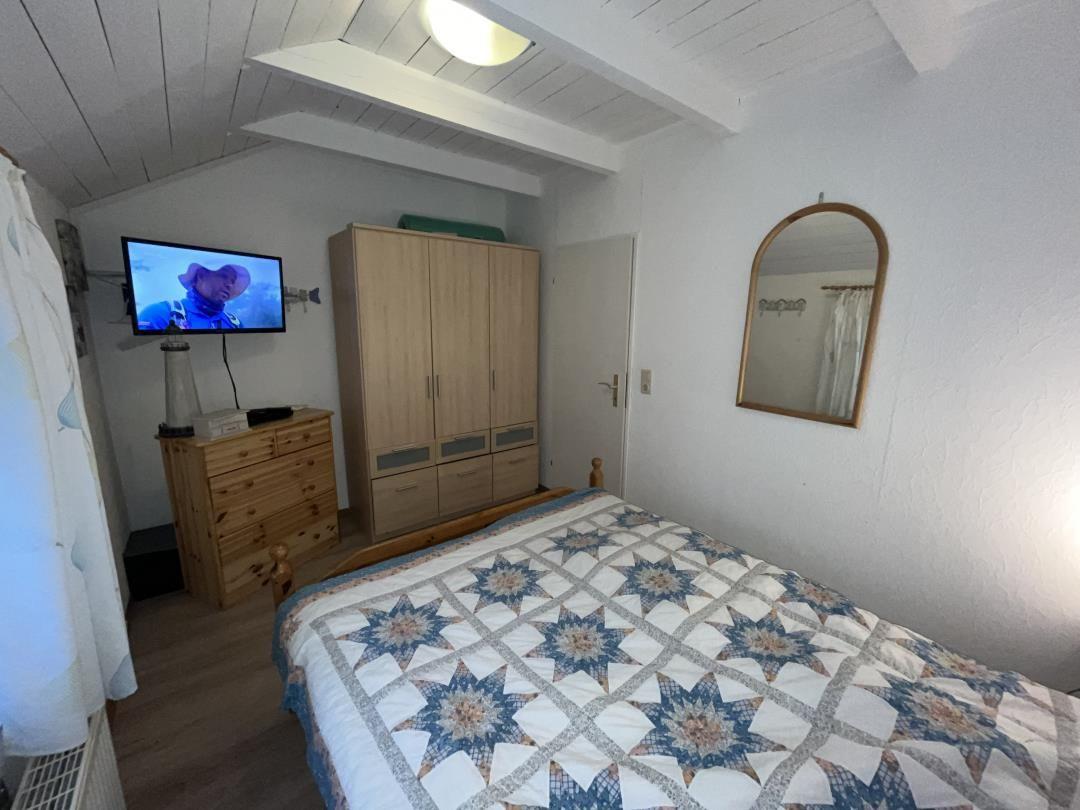 Bedroom with bed, wardrobe, and TV mounted on the wall.