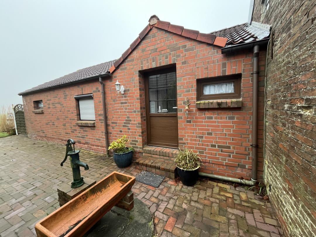 Red brick building with entrance door and plants in the garden.