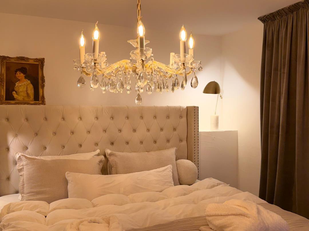 Bedroom with bed, chandelier, and wall picture.