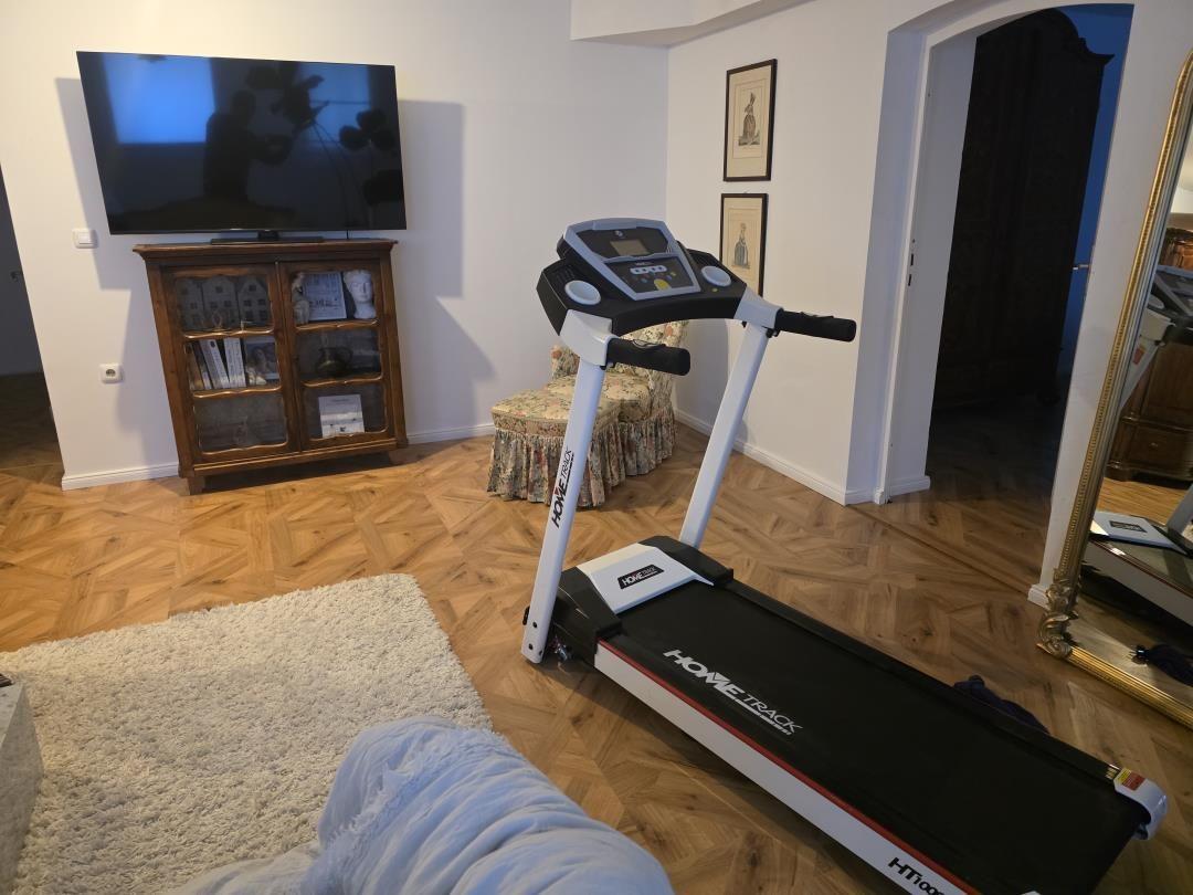 Vaulted room with treadmill, TV, and wooden floor