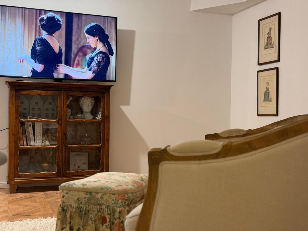 A living room with a TV, a wooden cabinet, and two armchairs.