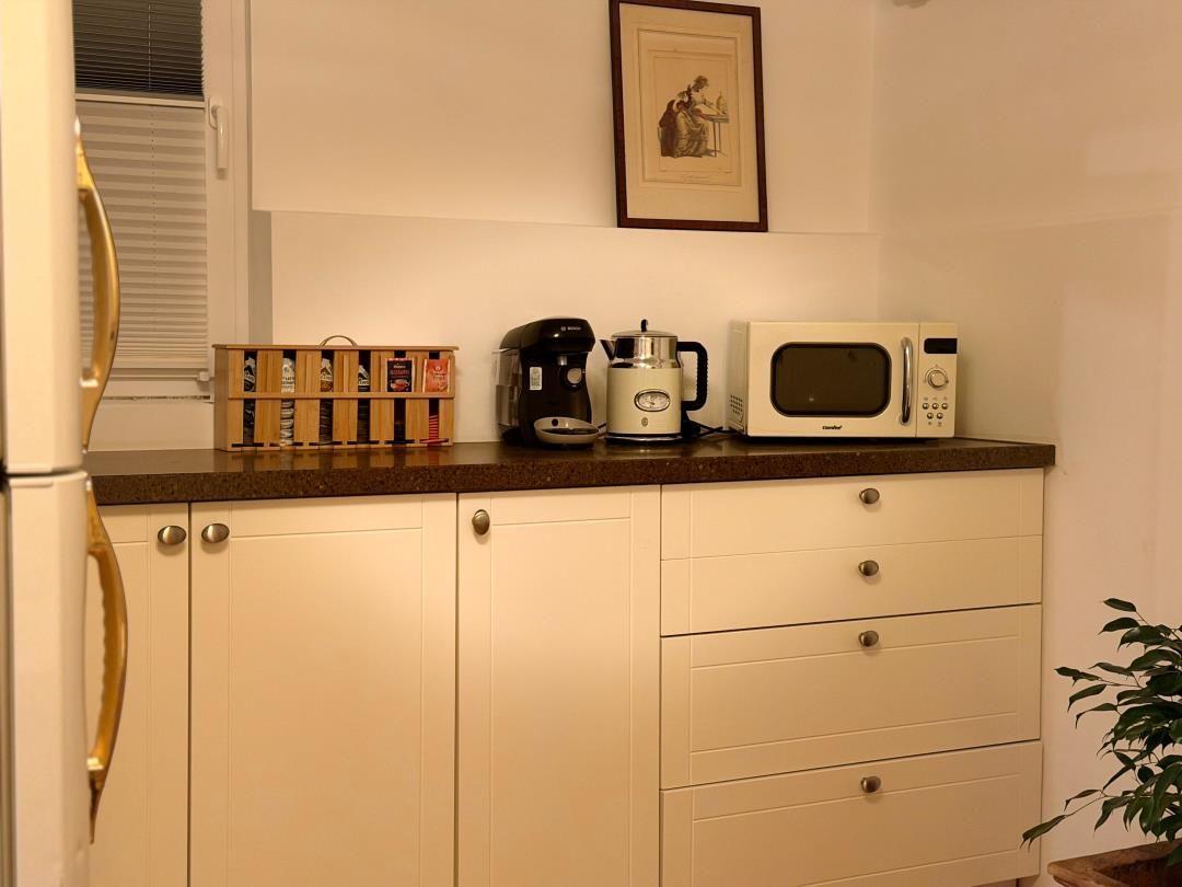 Kitchen counter with refrigerator, microwave, and coffee machine.