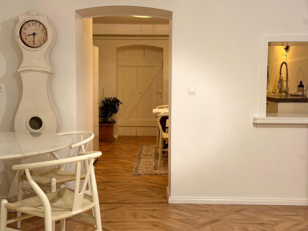 Dining area with table, chairs, and wall clock. Passage to living and kitchen areas.